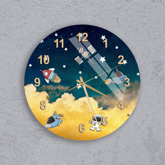 A wall clock with a space-themed design, featuring a rocket ship, a satellite, and an astronaut.