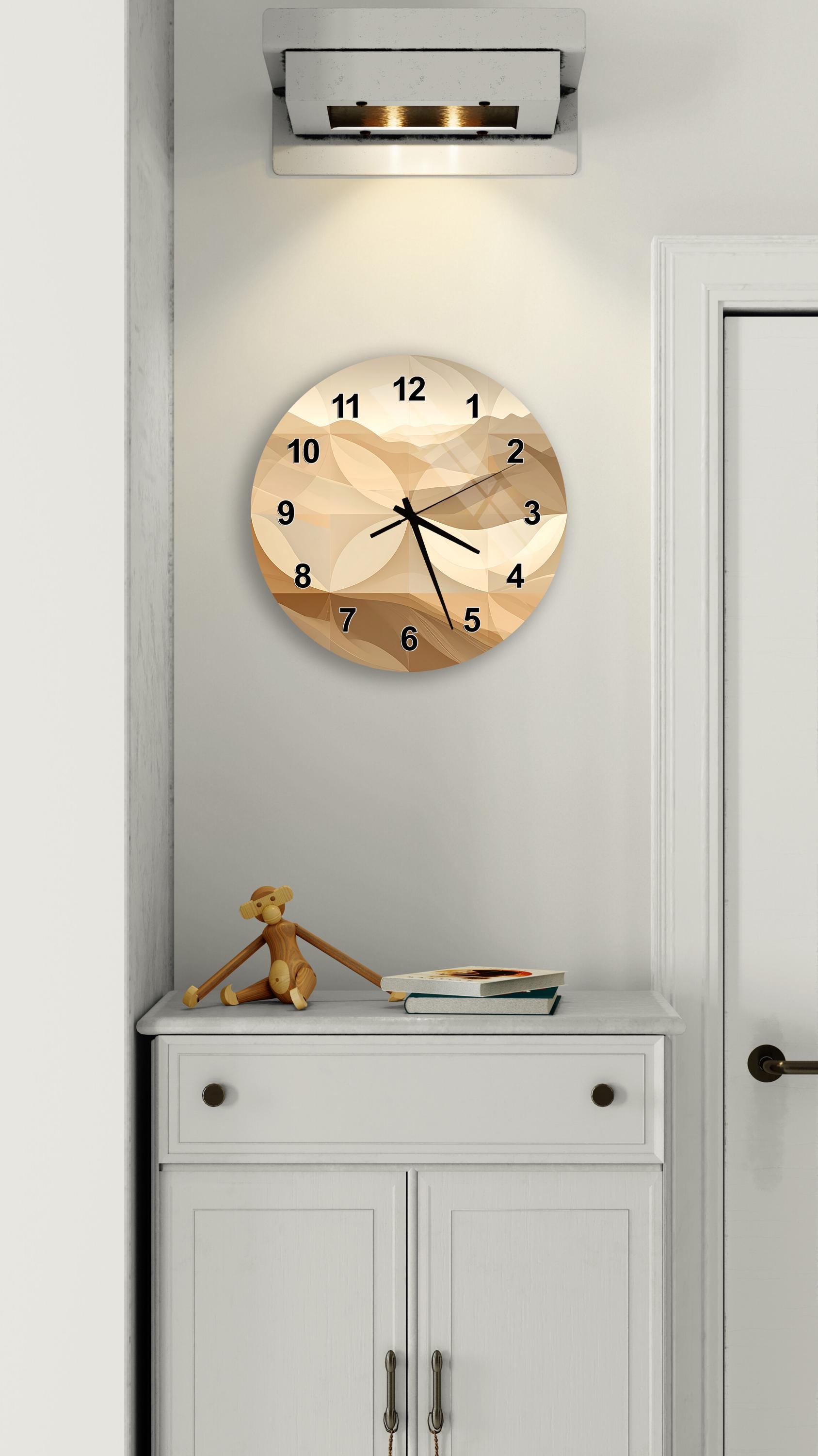 a wall clock with a beige and brown abstract design, mounted on a white wall above a white cabinet.