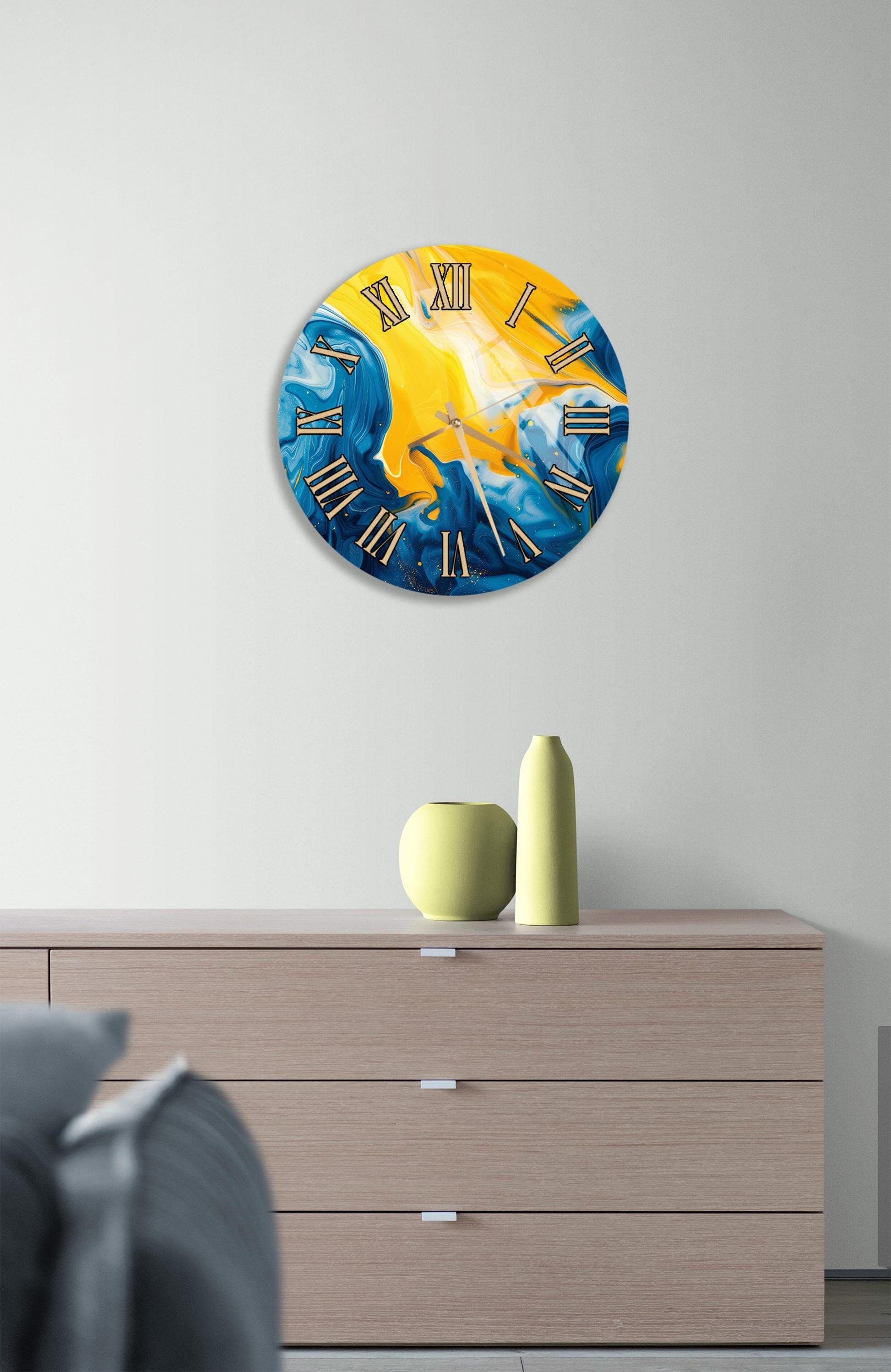 a modern clock with a vibrant blue and yellow design, hanging on a wall above a wooden dresser.