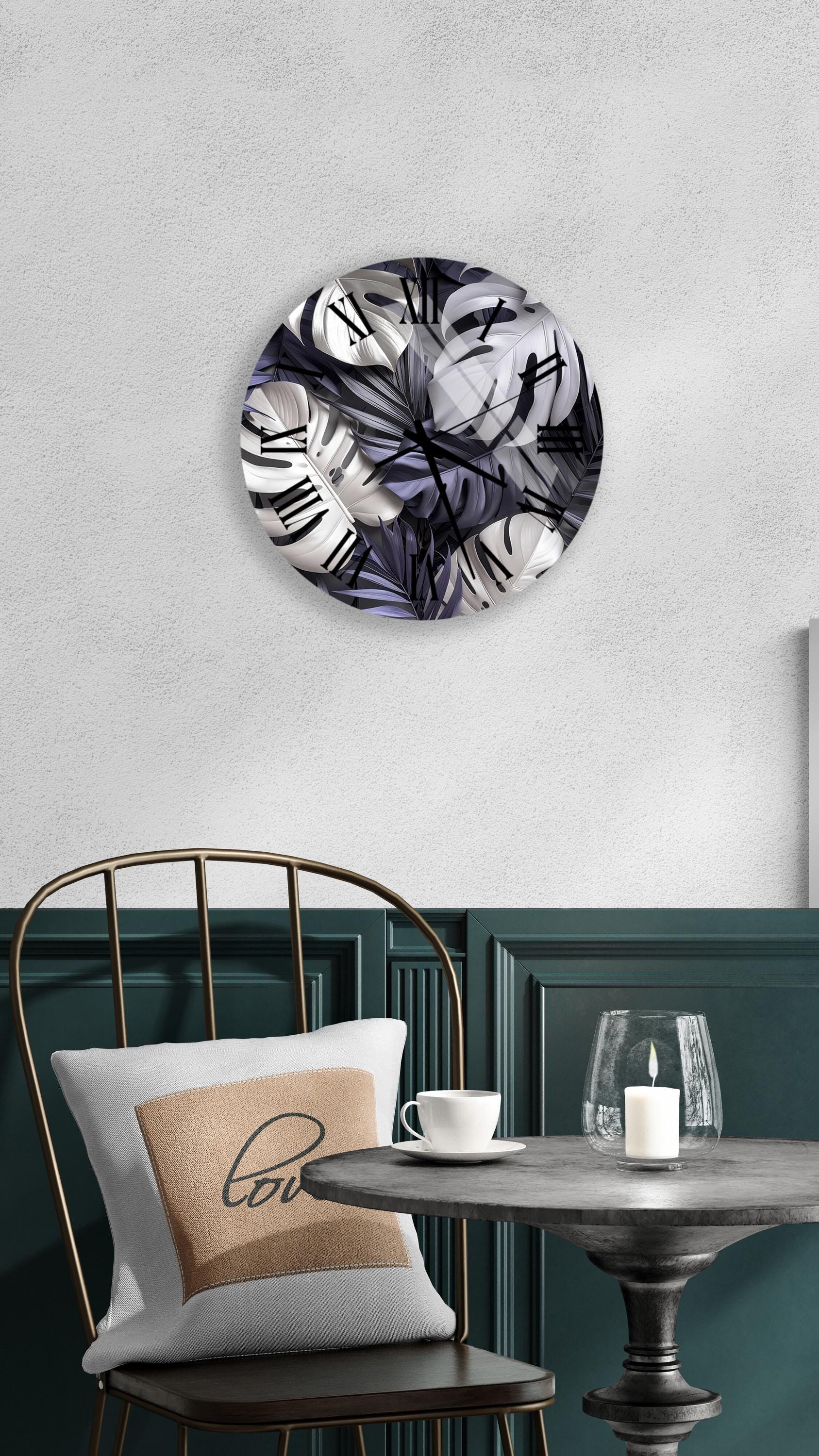 a modern and stylish interior design with a round wall clock displaying a floral pattern, a white table with a candle and a cup, and a black metal chair with a pillow.