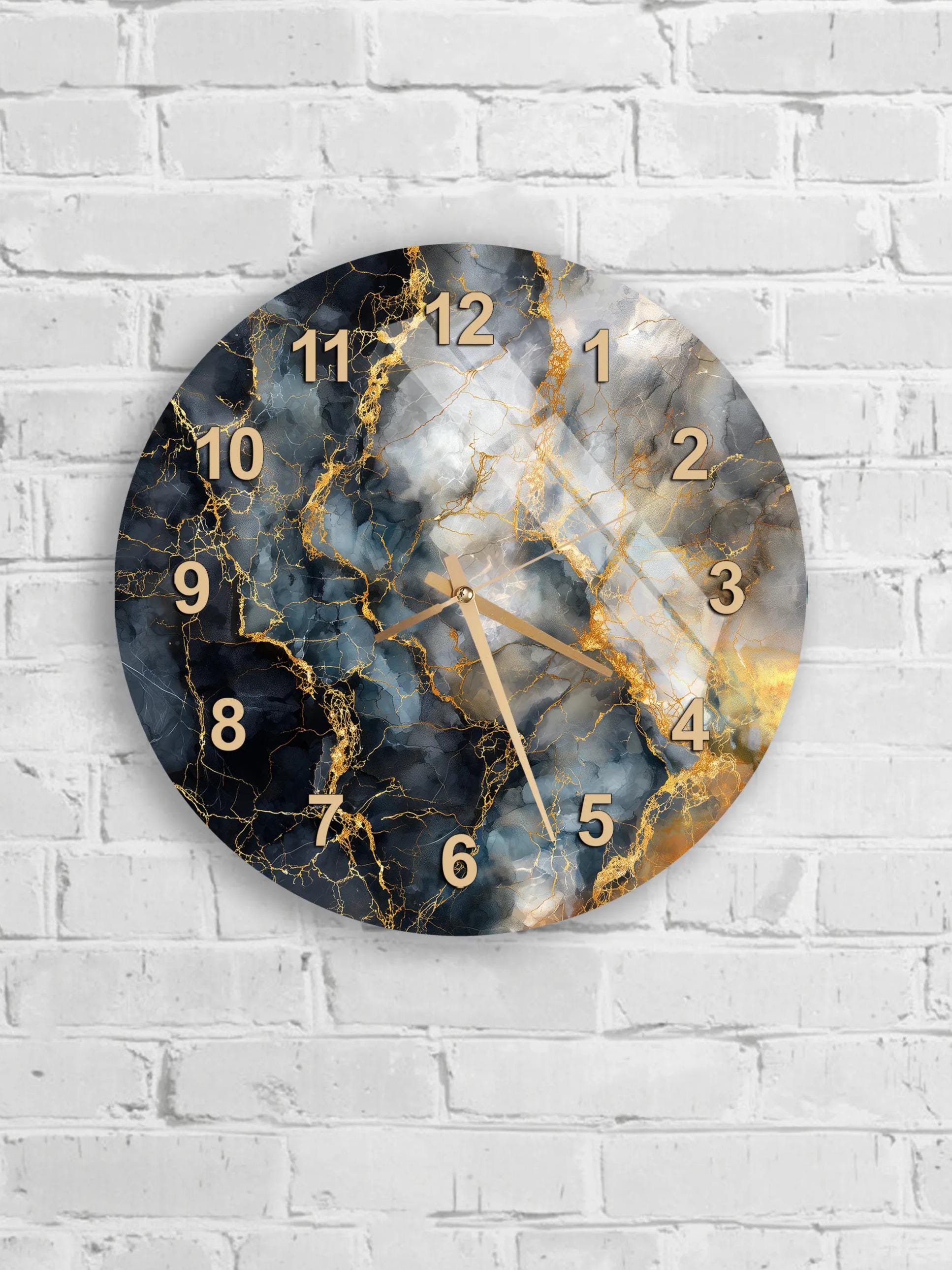 A round wall clock with a marble-like design and gold numbers is mounted on a white brick wall.