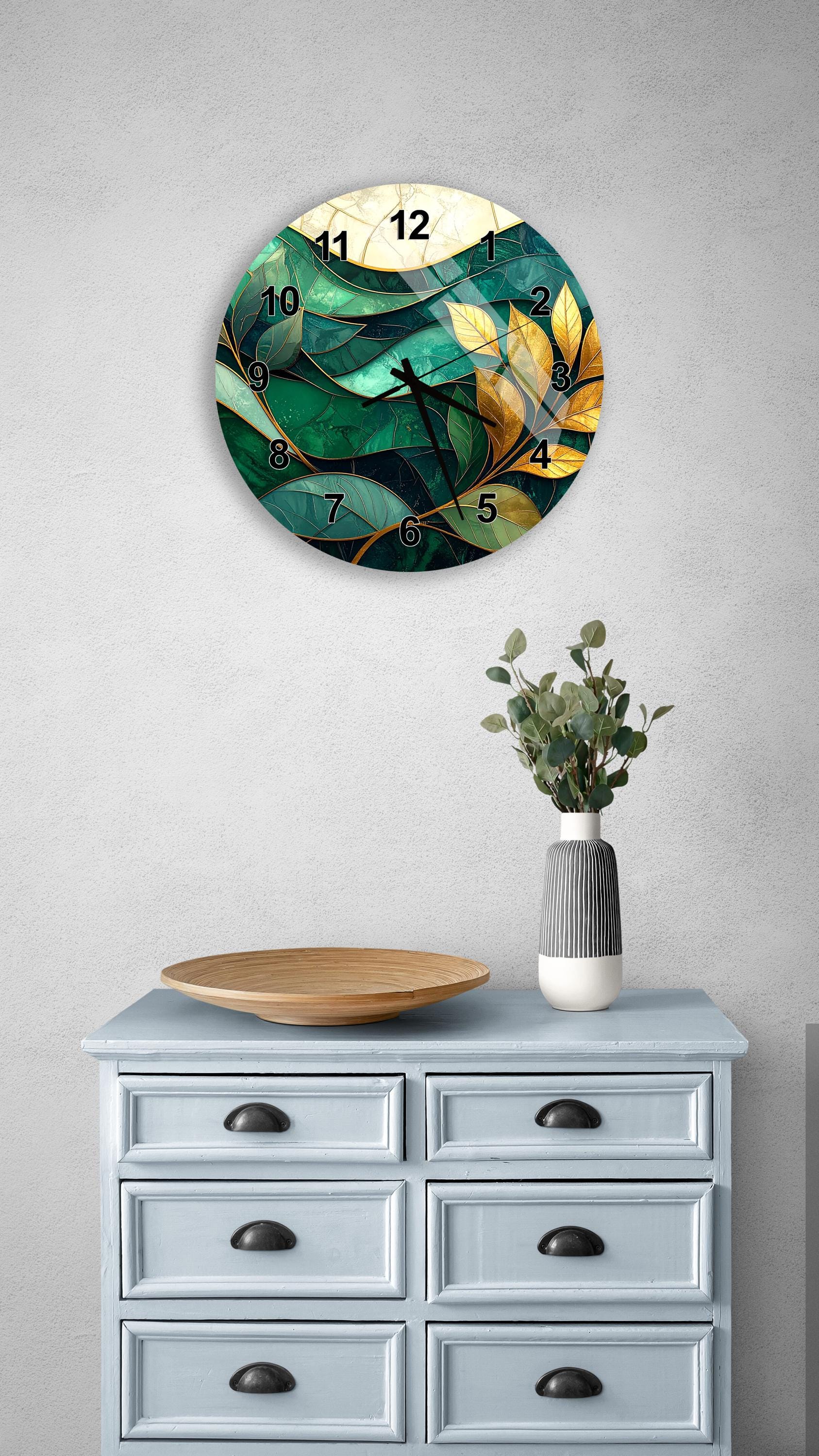 a wall clock with a green and yellow leaf design, mounted on a wall above a light blue dresser with six drawers. The dresser also has a vase with greenery and a wooden tray on top.
