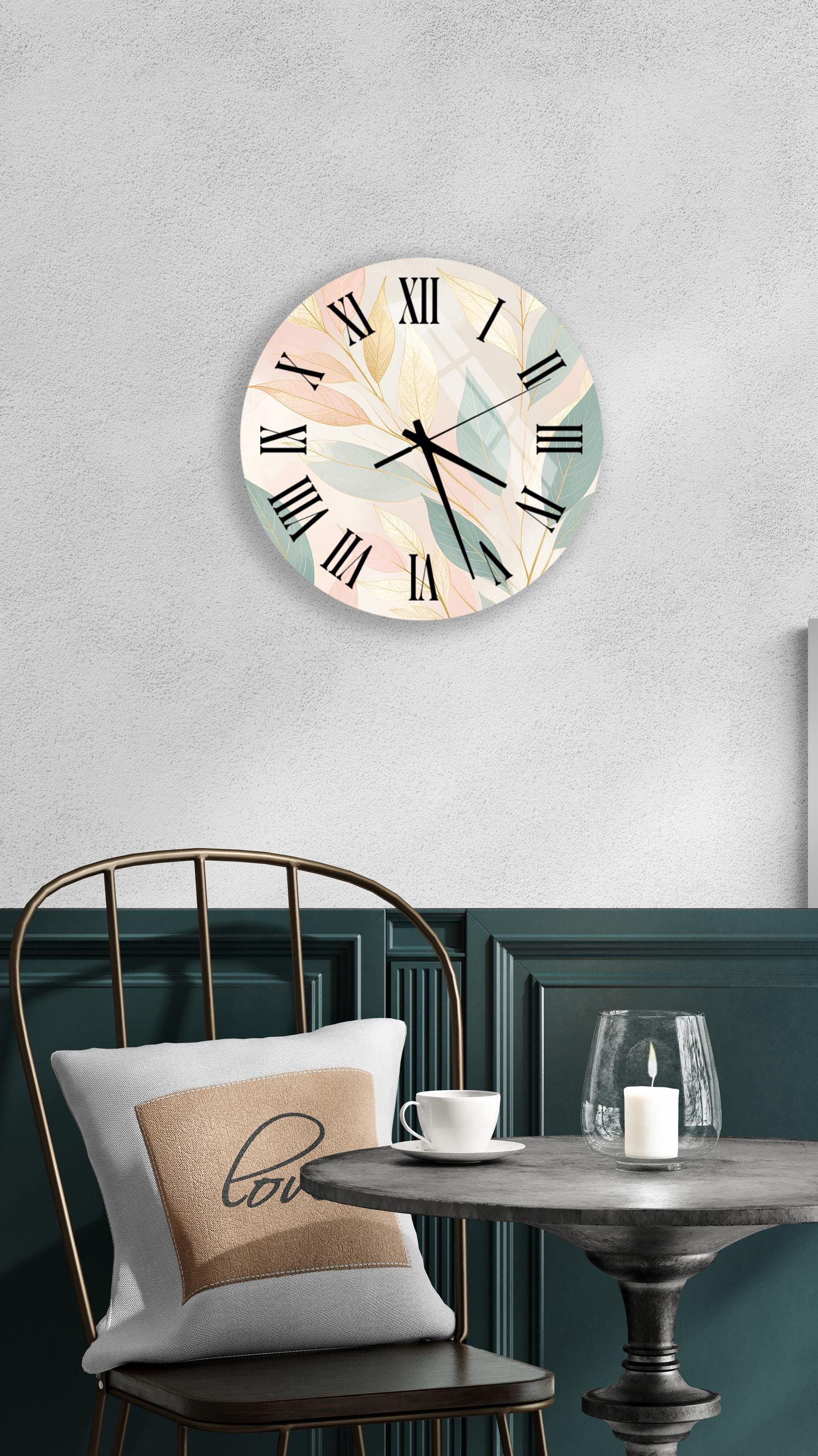 a wall clock with a floral design, a round table with a white cup and a candle, and a chair with a pillow on it.