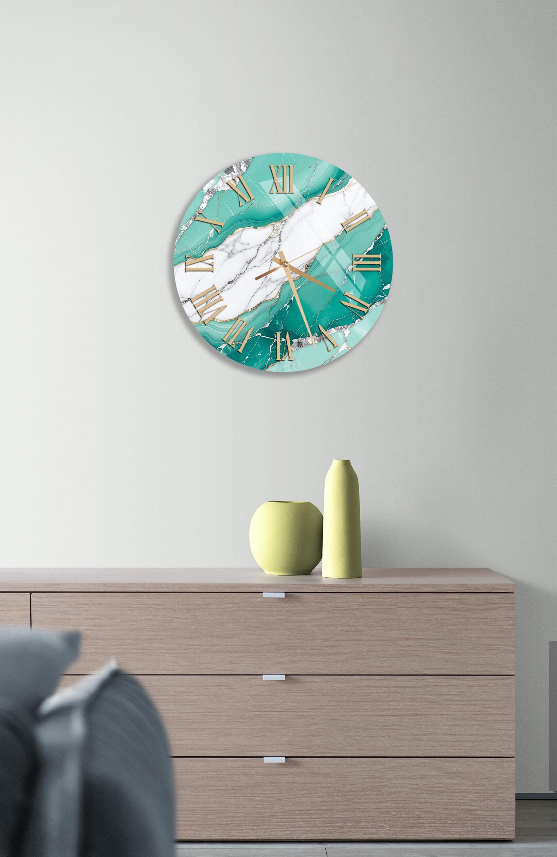 a modern living room with a large turquoise and white marble wall clock hanging above a wooden dresser. The dresser has a vase and a bottle on top, adding a decorative touch to the space.
