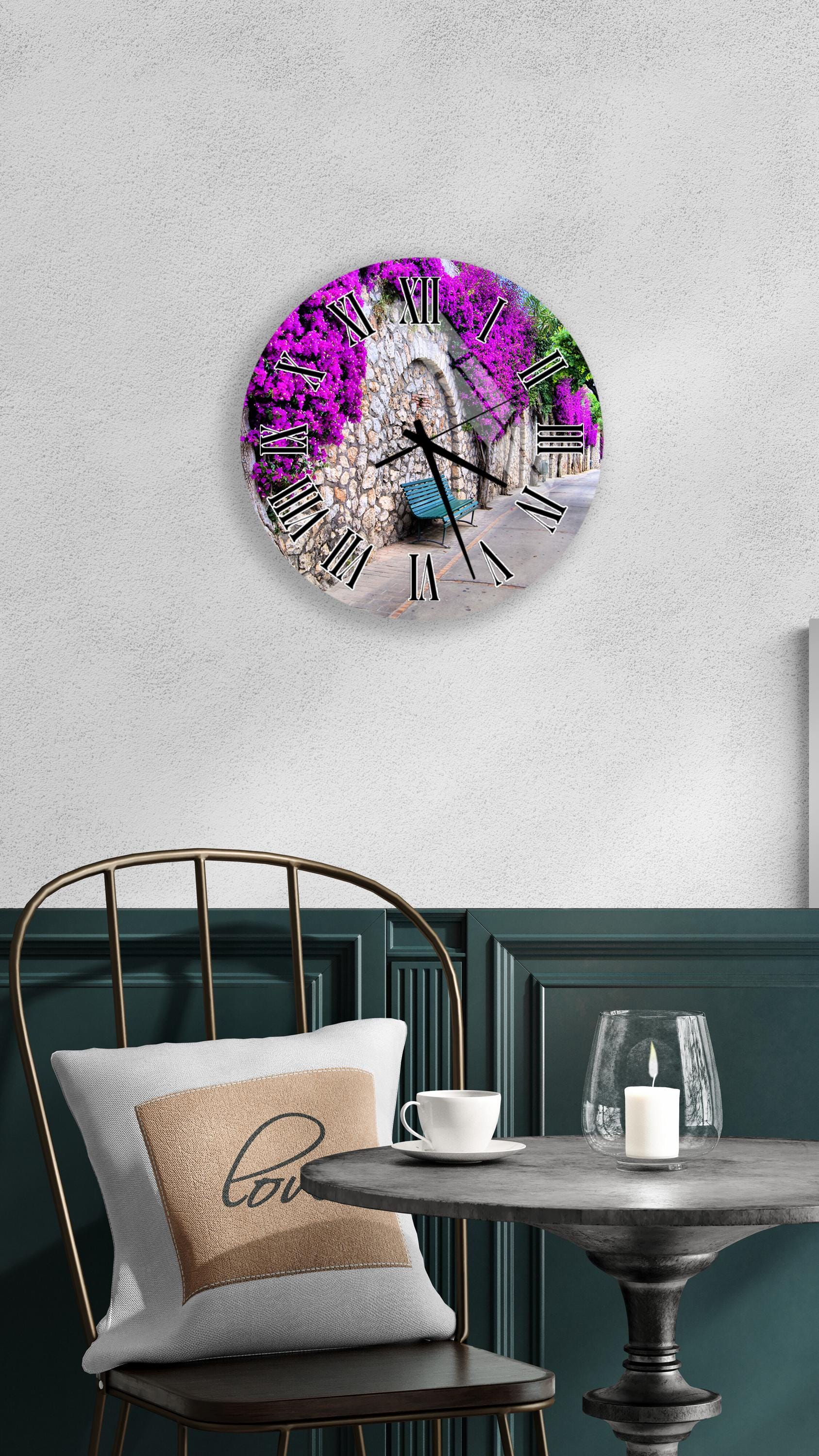 a round wall clock with a vibrant purple floral design, mounted on a white wall above a dining table with a white tablecloth.