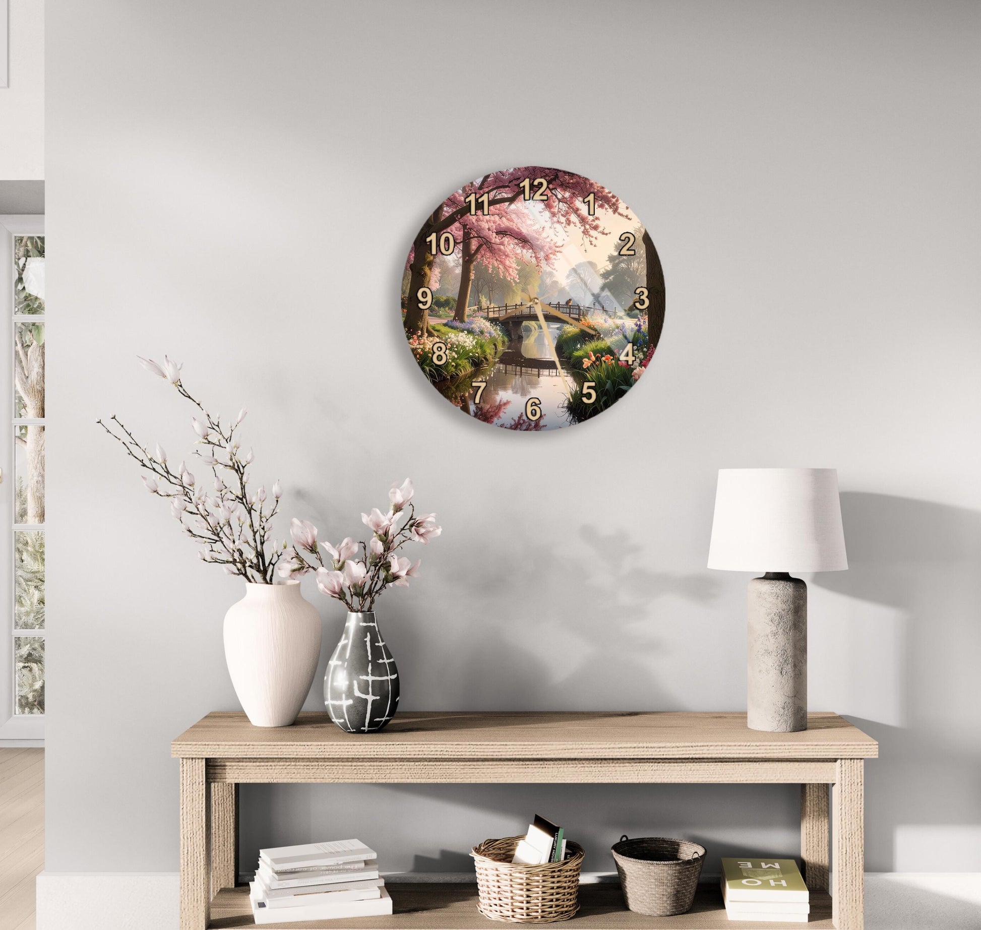 a wall clock with a floral design, a wooden table with a lamp, a vase with flowers, and some books on a shelf.