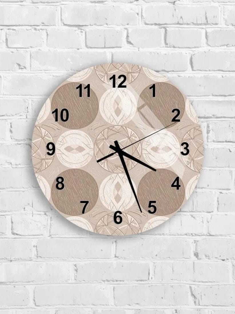A round wall clock with a beige and brown patterned design, mounted on a white brick wall.