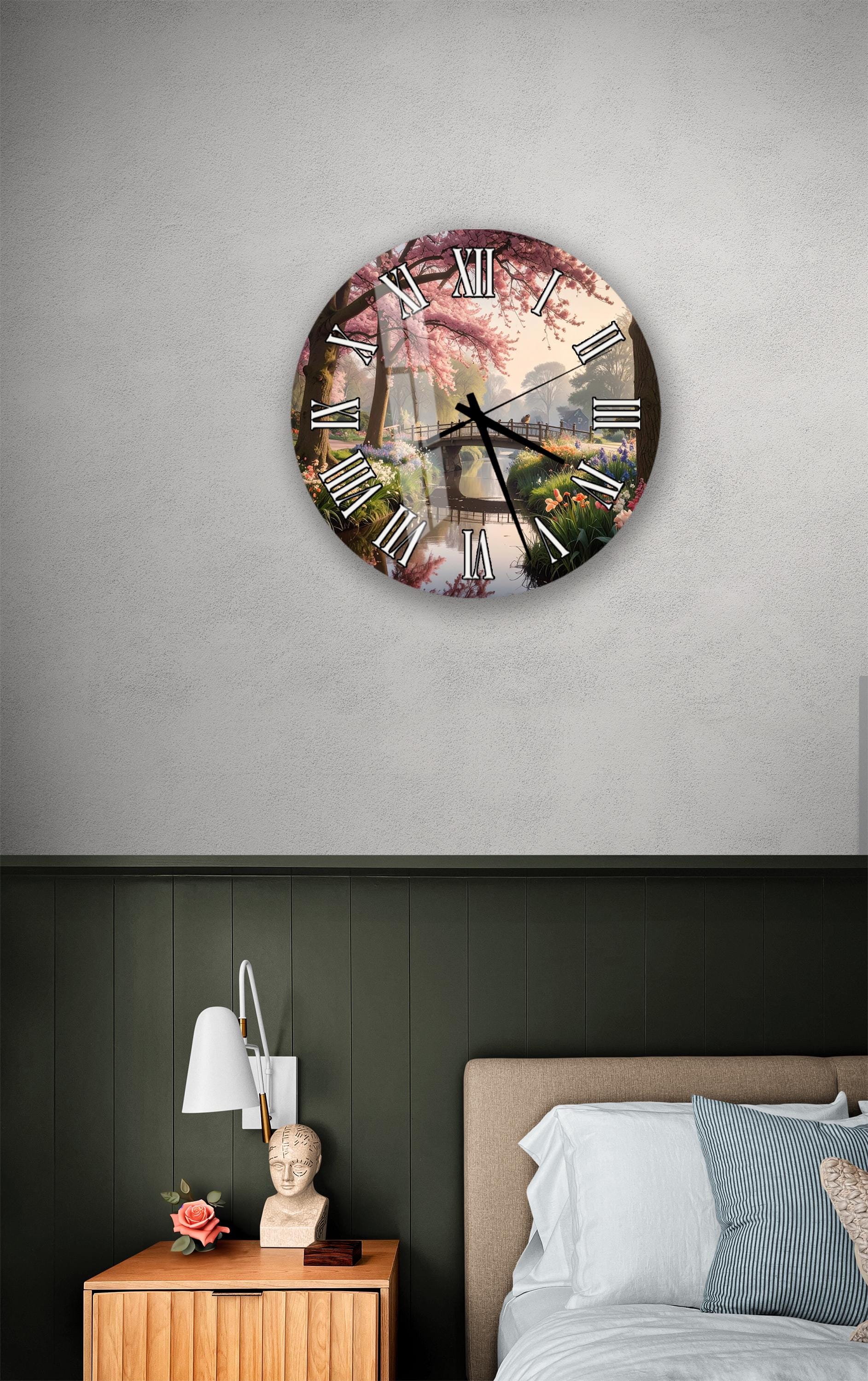 a clock with a floral design on the face, mounted on a wall above a bedside table with a lamp and a small statue.