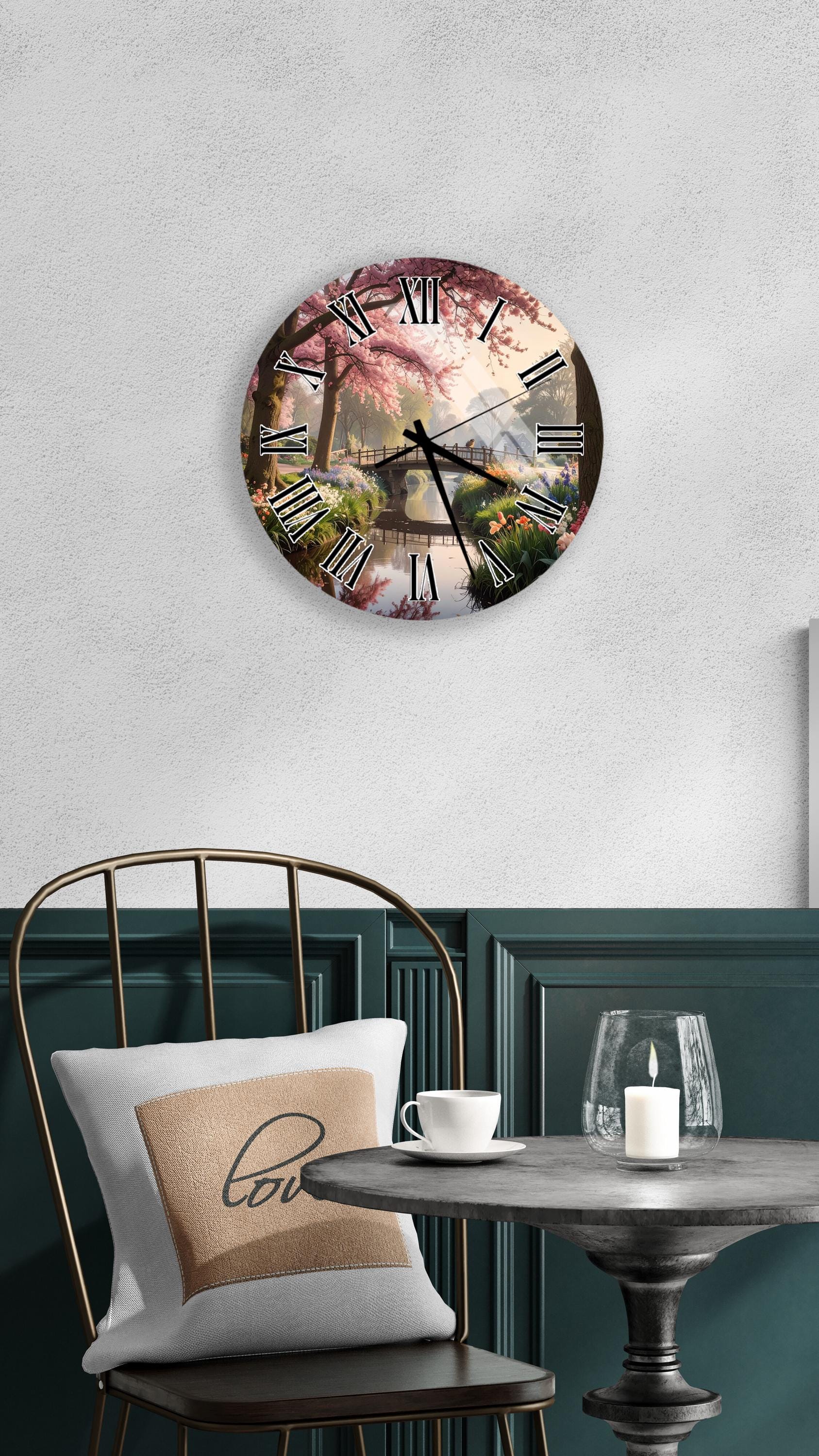 a wall clock with a floral design, a white table with a candle and a cup, and a green chair with a pillow.
