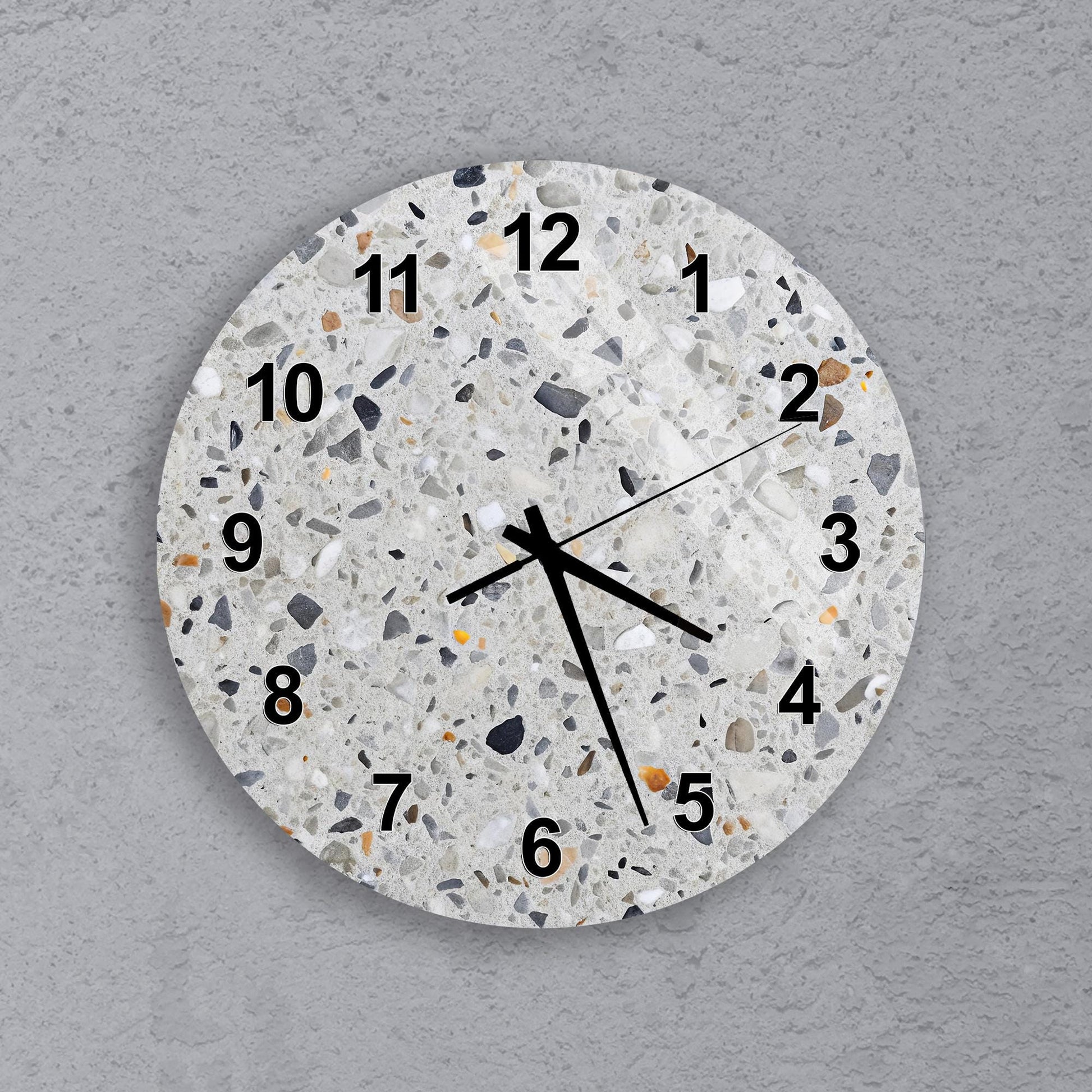 A round wall clock with a terra cotta-like texture and black numbers on a gray background.