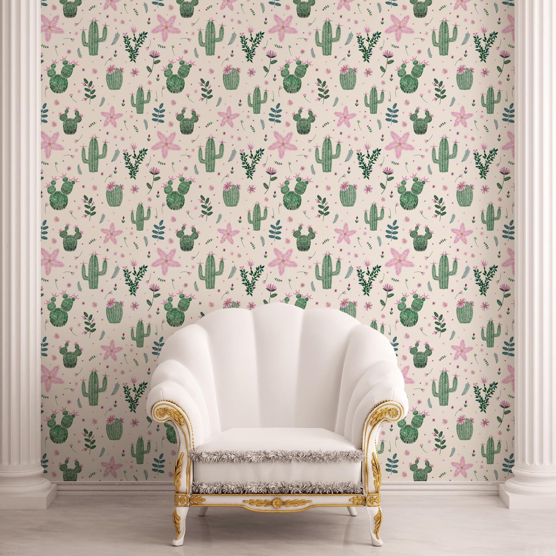 a white upholstered armchair with gold trim, positioned in front of a wall with a repeating pattern of cacti and other plants in shades of pink and green.