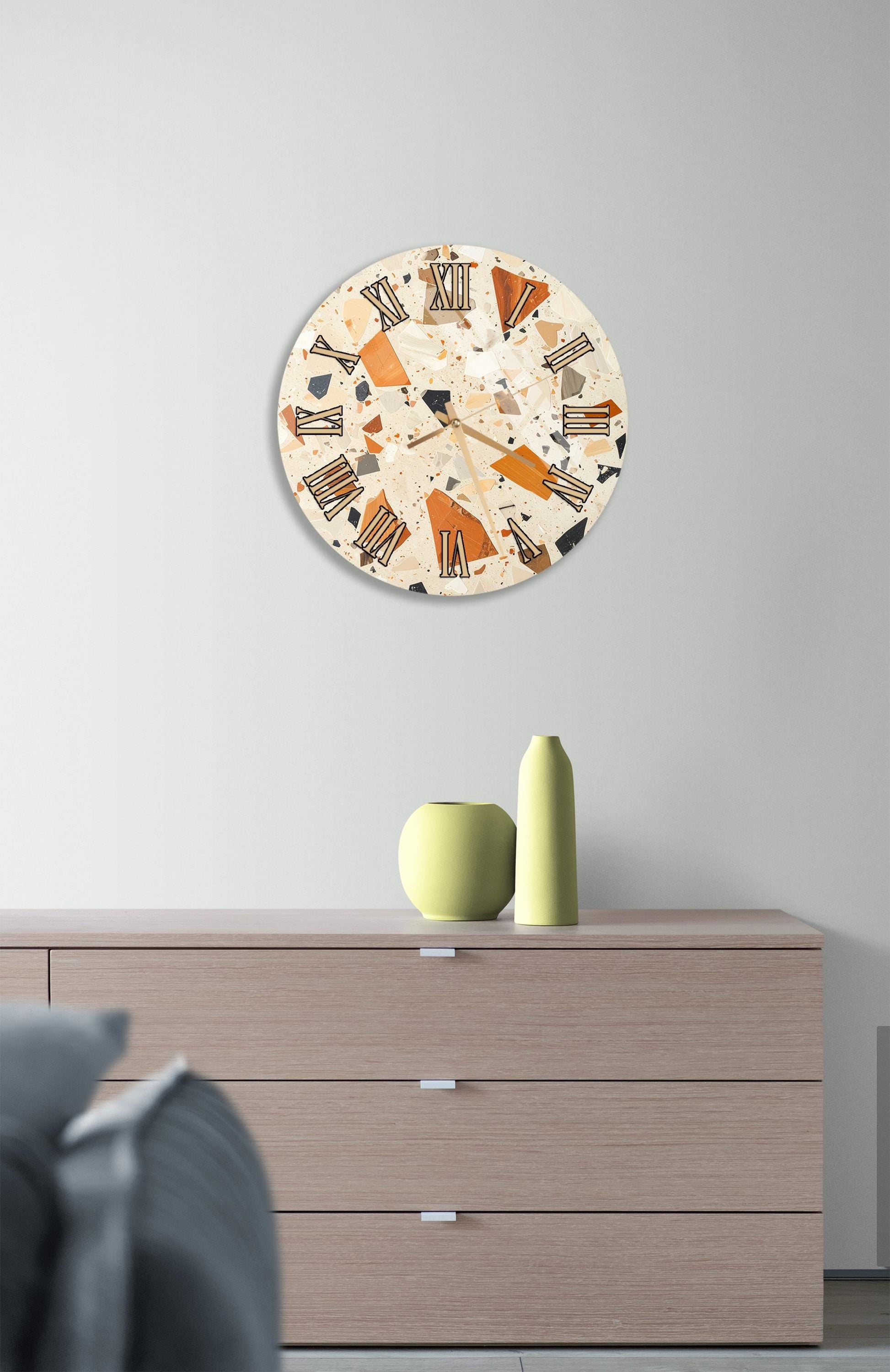 a modern interior design with a round clock on a wall above a wooden dresser. The dresser has three drawers and a vase on top.