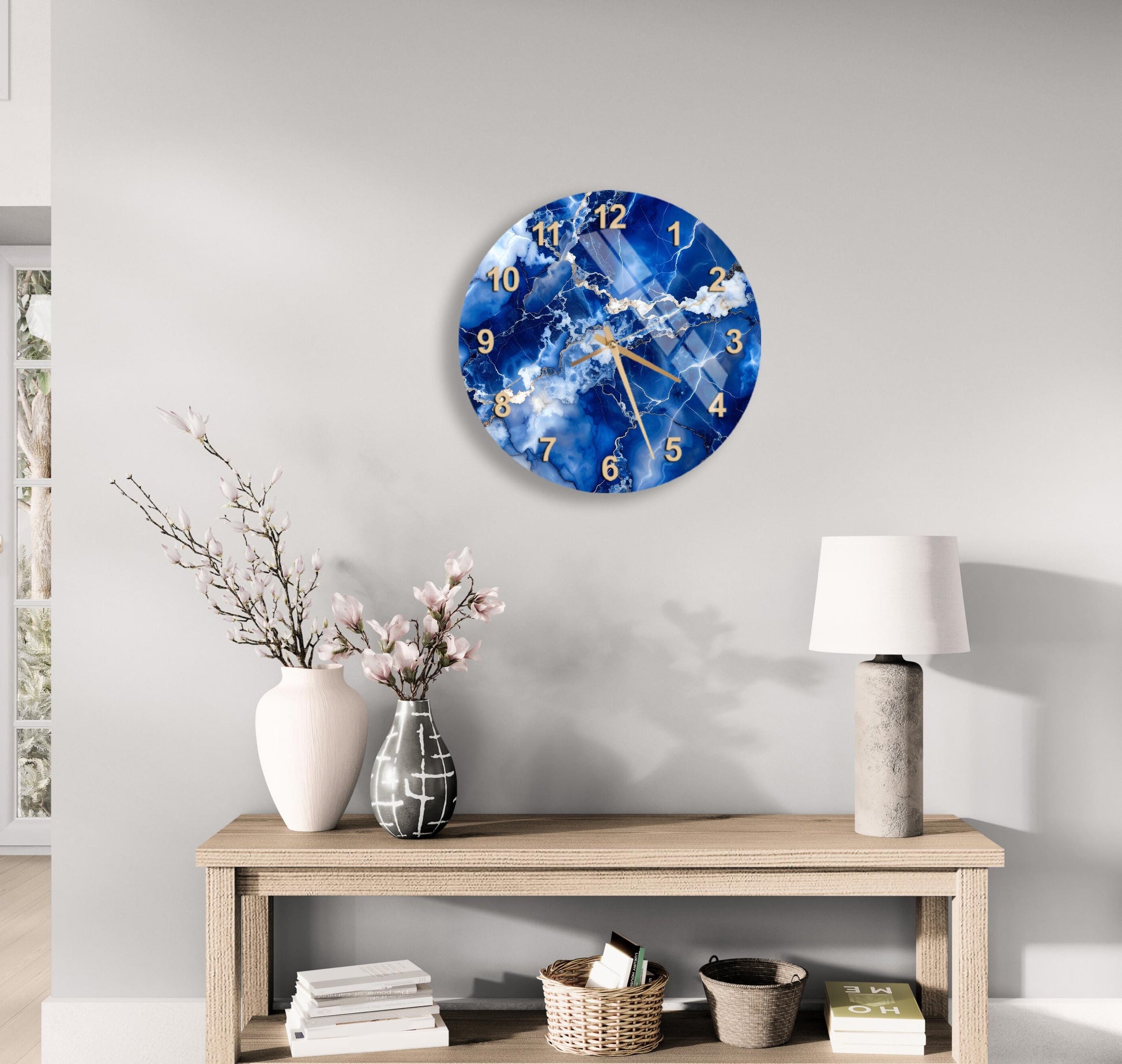 a modern living room with a wooden table, a white vase with pink flowers, a round clock with a blue and white marble design, and a lamp on the table.