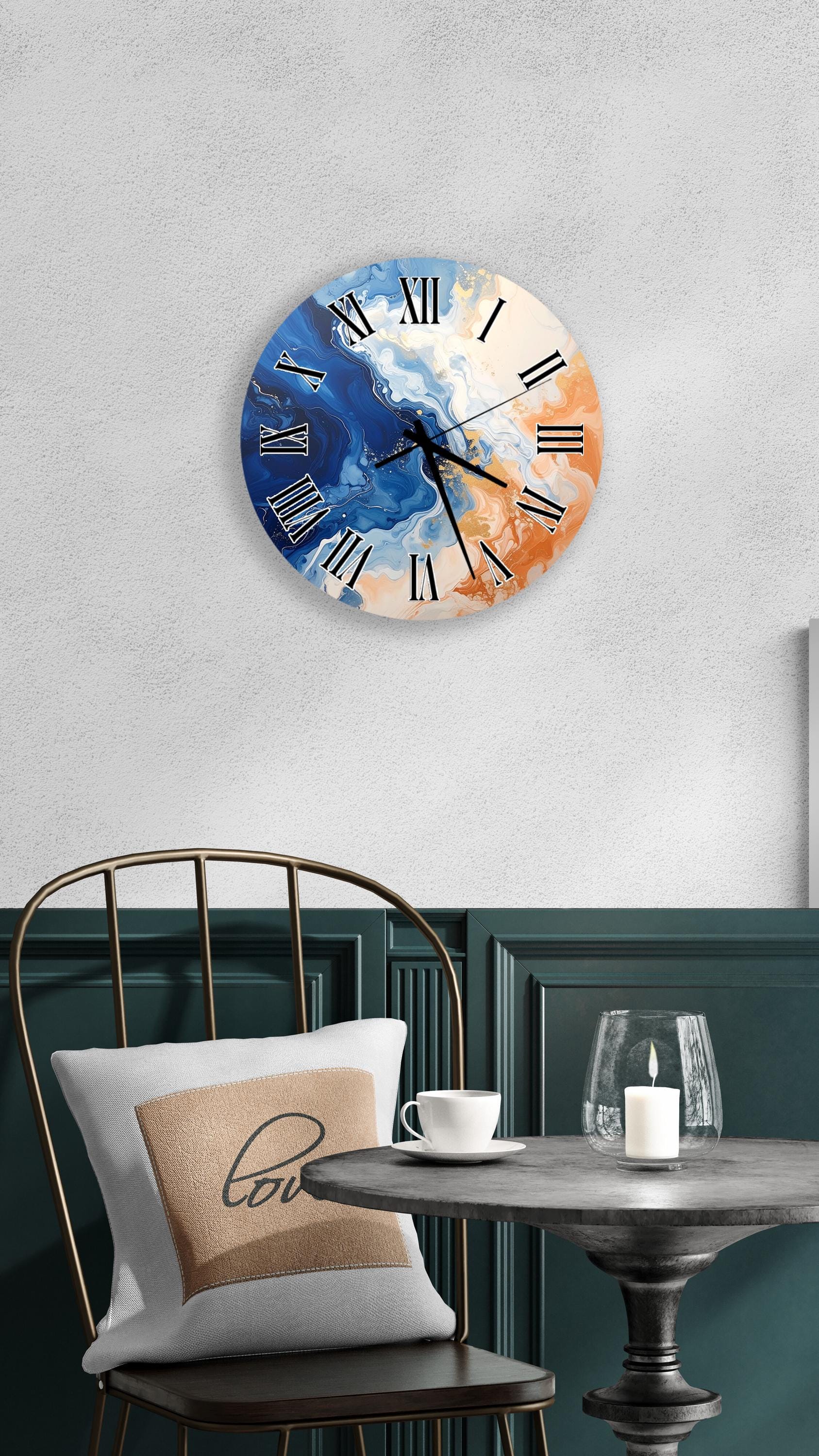 a wall clock with a blue and orange color scheme, hanging on a wall above a table with a white tablecloth. The table has a white cup and a candle on it, creating a cozy and inviting atmosphere.