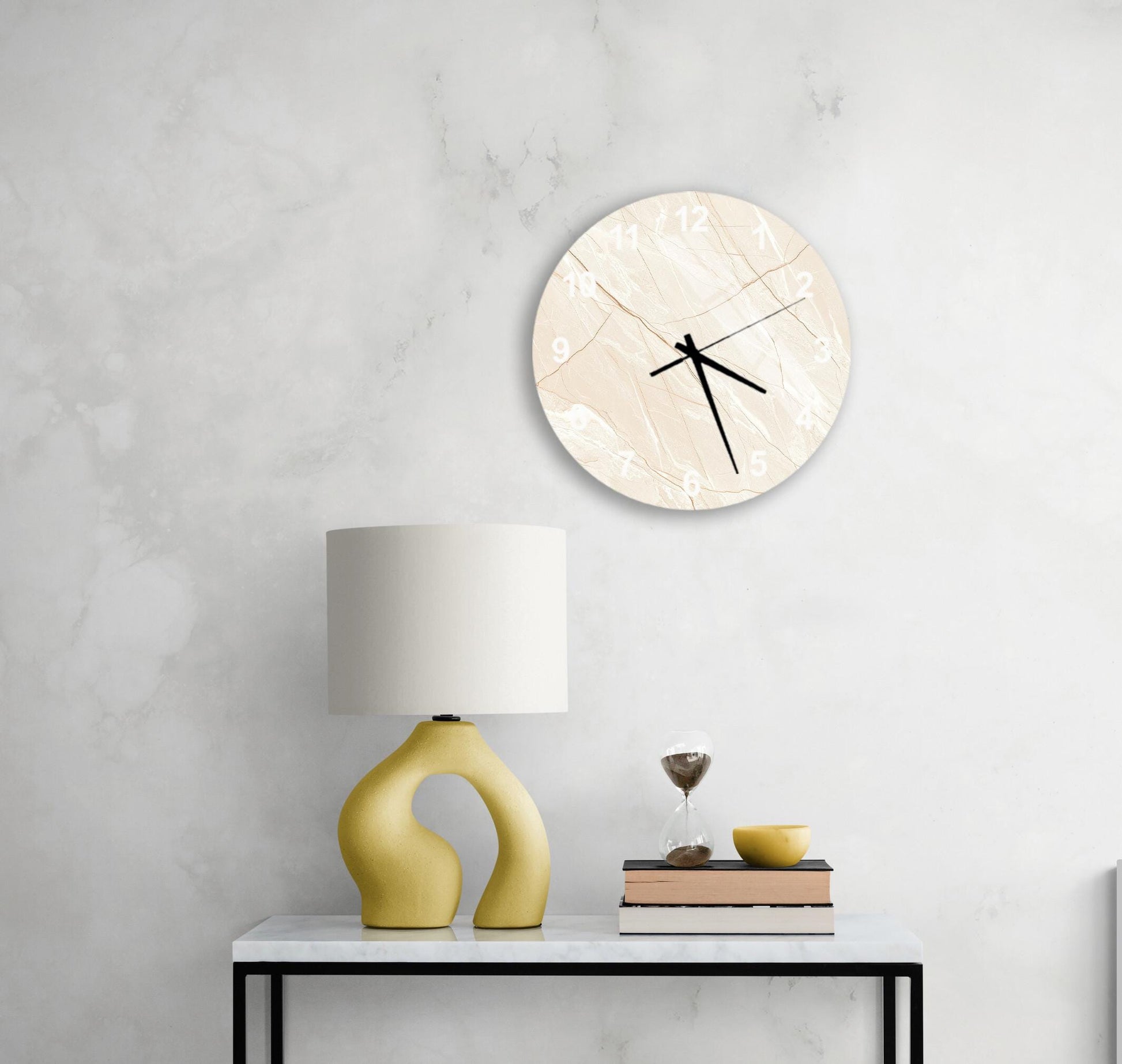 a modern living room with a white marble wall, a round clock with a unique design, a yellow lamp with a curved base, a stack of books, and a glass of wine on a white table.