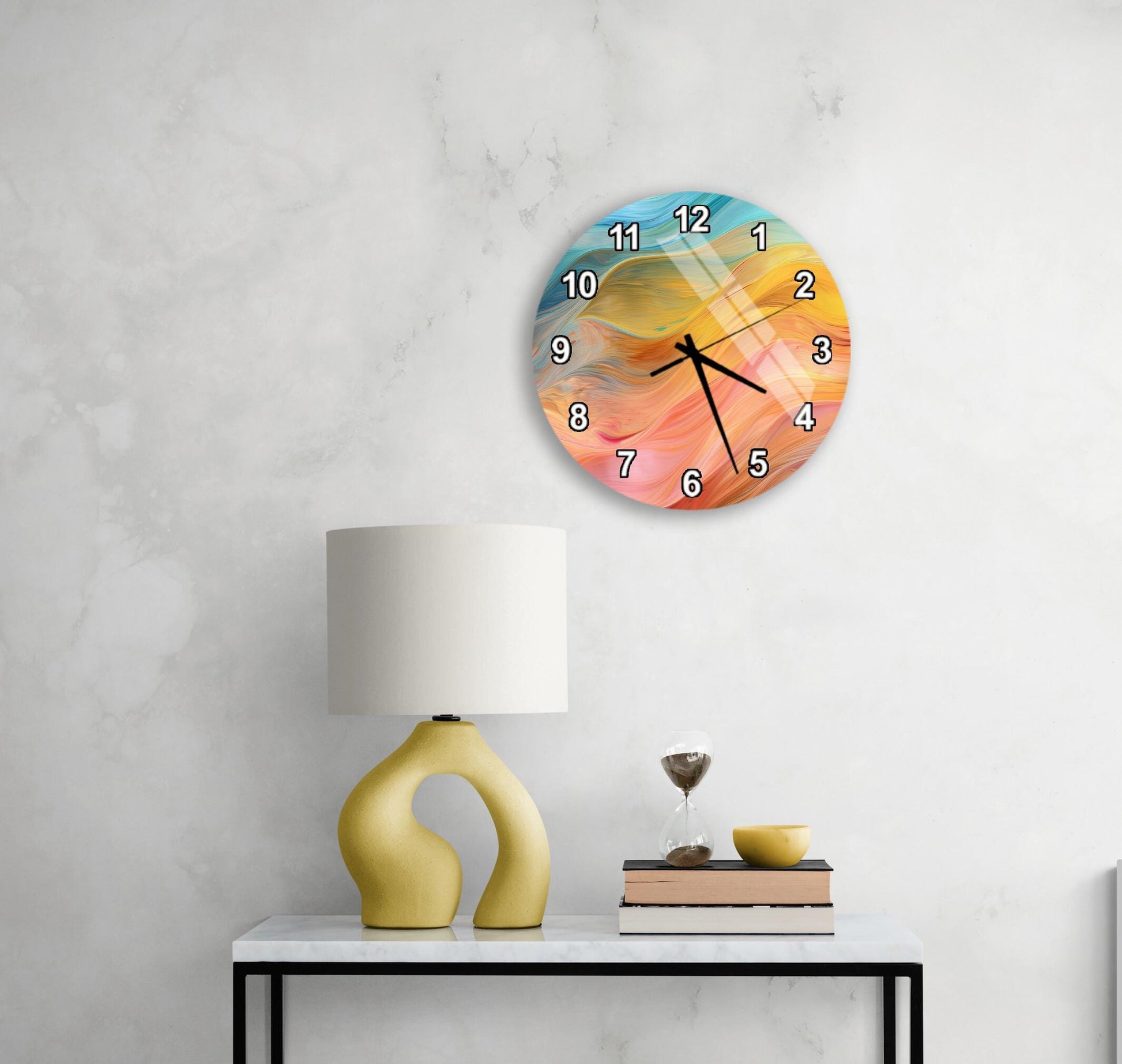 a wall clock with a colorful abstract design, a yellow lamp on a table, and a stack of books and a glass of water on the table.