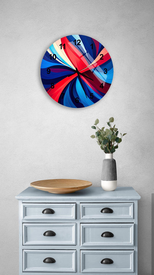 a wall clock with a vibrant, abstract design in red, blue, and white colors, mounted on a wall above a light blue dresser with six drawers. The dresser also has a small plant and a wooden bowl on it.