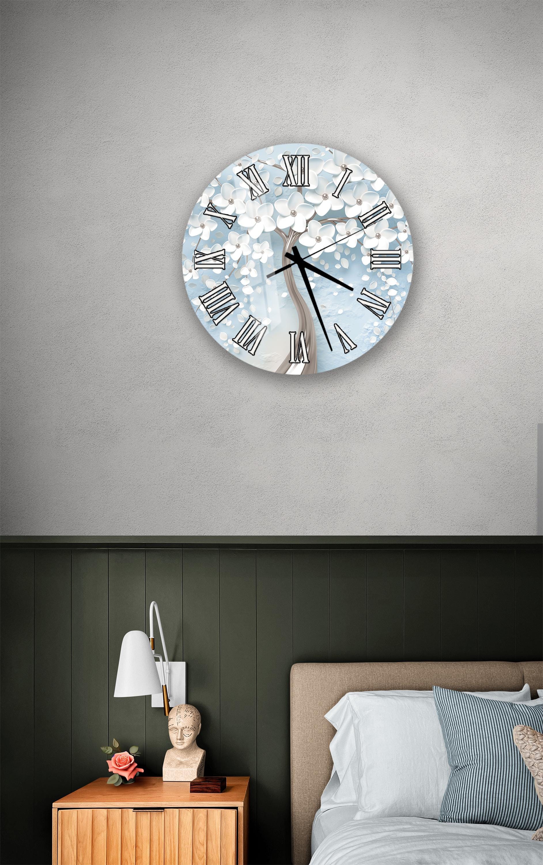 a bedroom setting with a wall clock displaying a floral design, a wooden nightstand with a lamp, and a bed with white bedding.