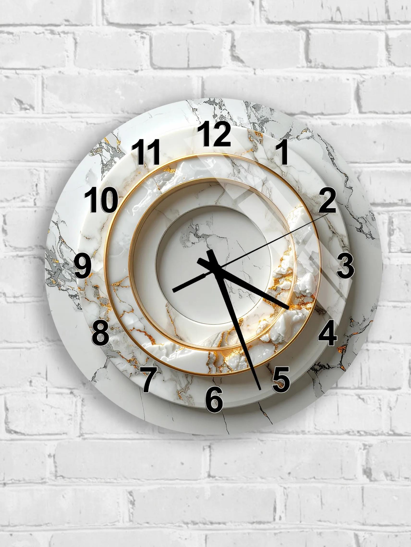 A modern, stylish wall clock with a marble-like design and gold accents, mounted on a white brick wall.