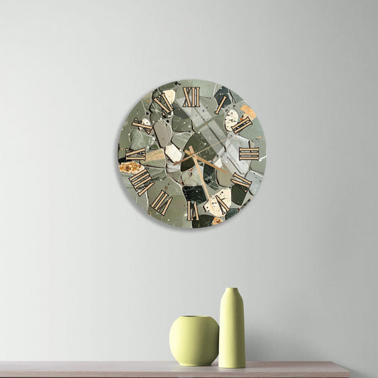 a modern clock with a mosaic design on a light-colored wall, accompanied by a wooden dresser and a small green vase.