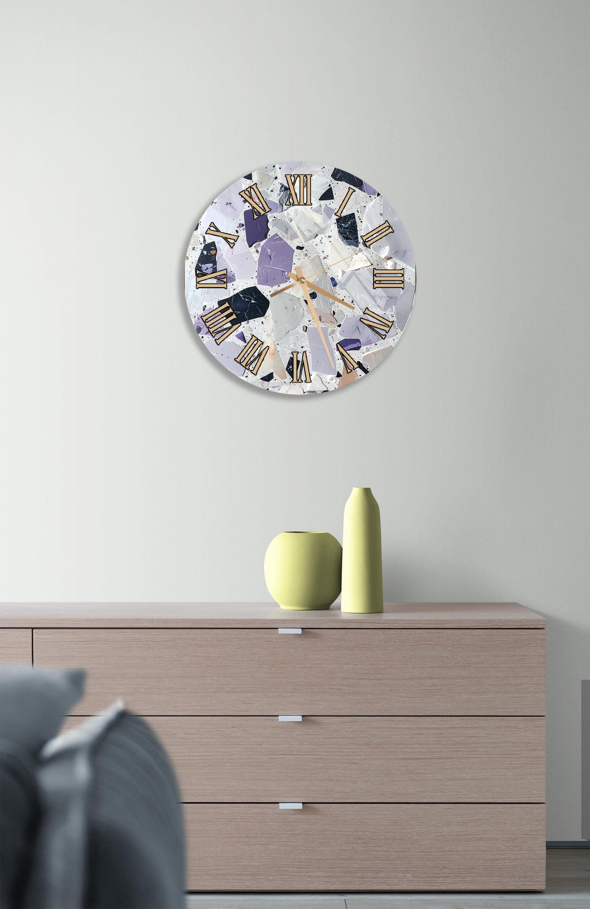a modern clock with a colorful, abstract design hanging on a wall above a wooden dresser.