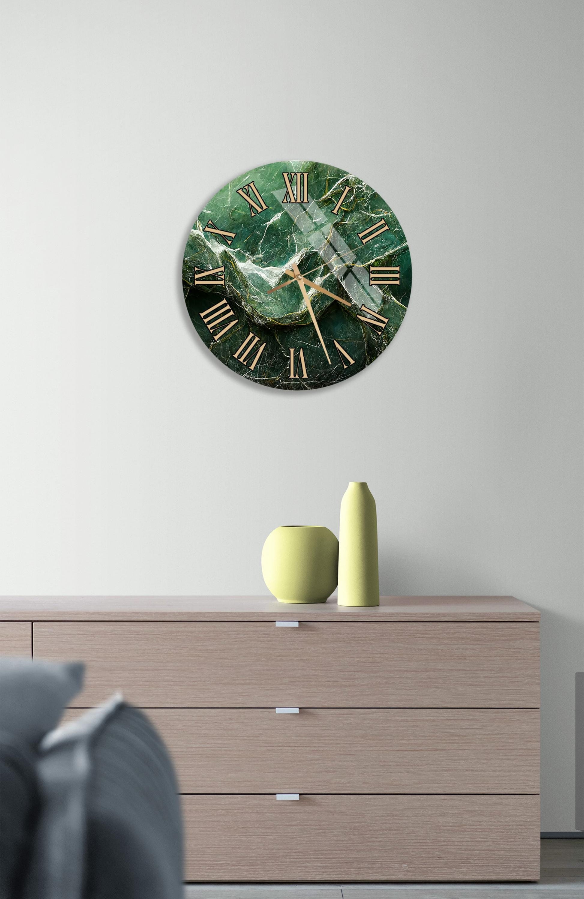 a modern living room with a large round clock with a green marble face hanging on the wall above a wooden dresser. The dresser has three drawers and a vase on top.