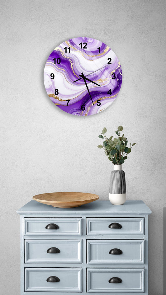 a wall clock with a purple and gold marble design, mounted on a wall above a light blue dresser with six drawers. The dresser also has a wooden tray and a vase with greenery on it.