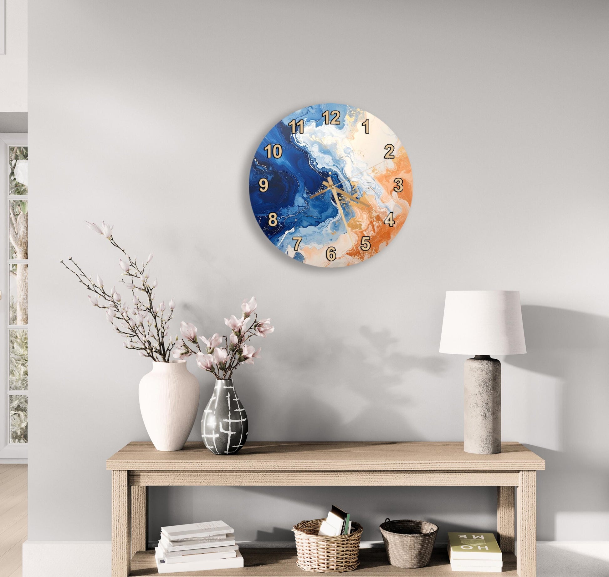a wall clock with a blue and orange design, a wooden table with a lamp, a vase with flowers, and some books on a shelf.