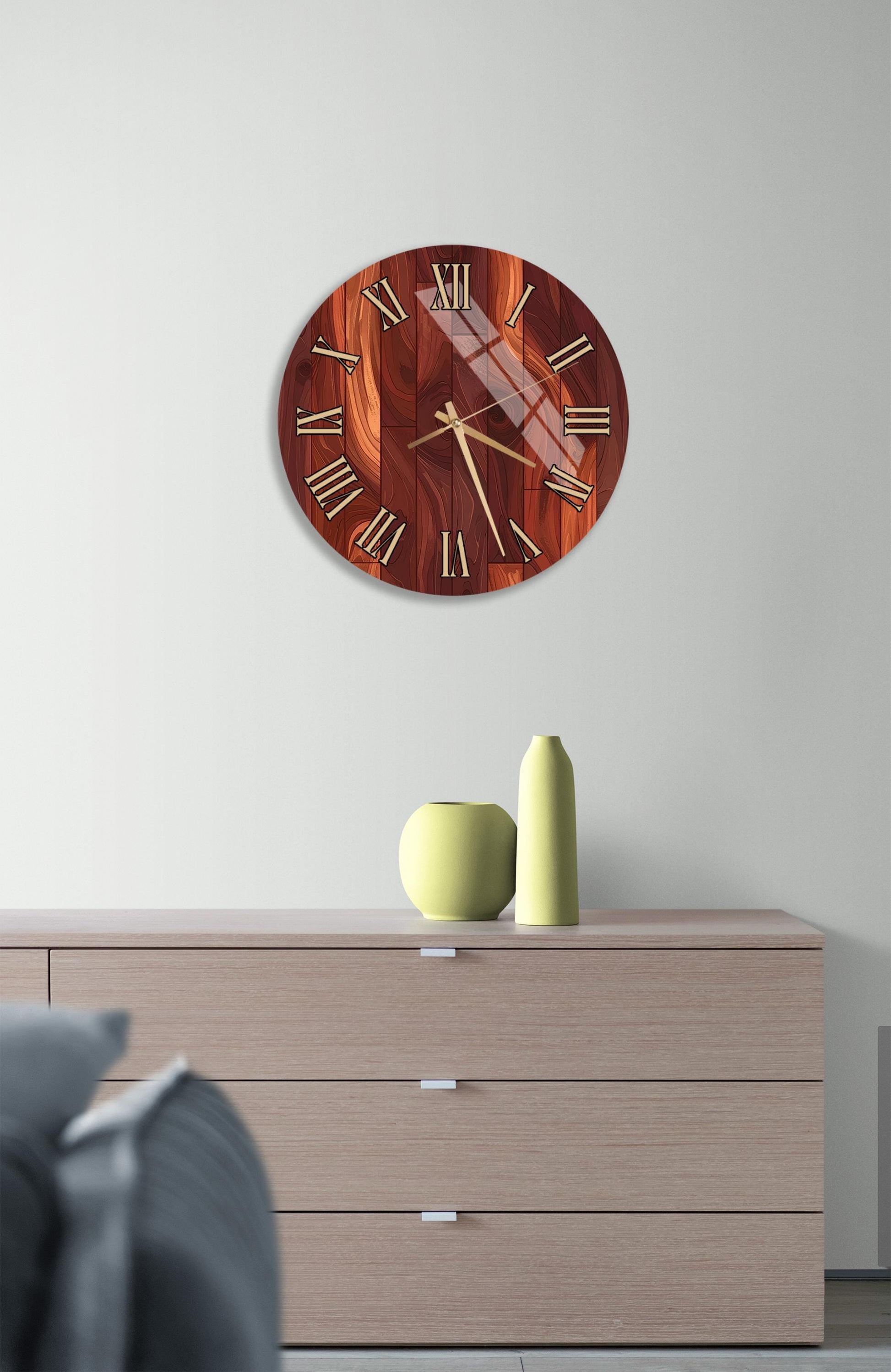 a wooden clock with a dark brown finish, mounted on a white wall above a wooden dresser with three drawers. The dresser also has a small green vase and a yellow vase on it.