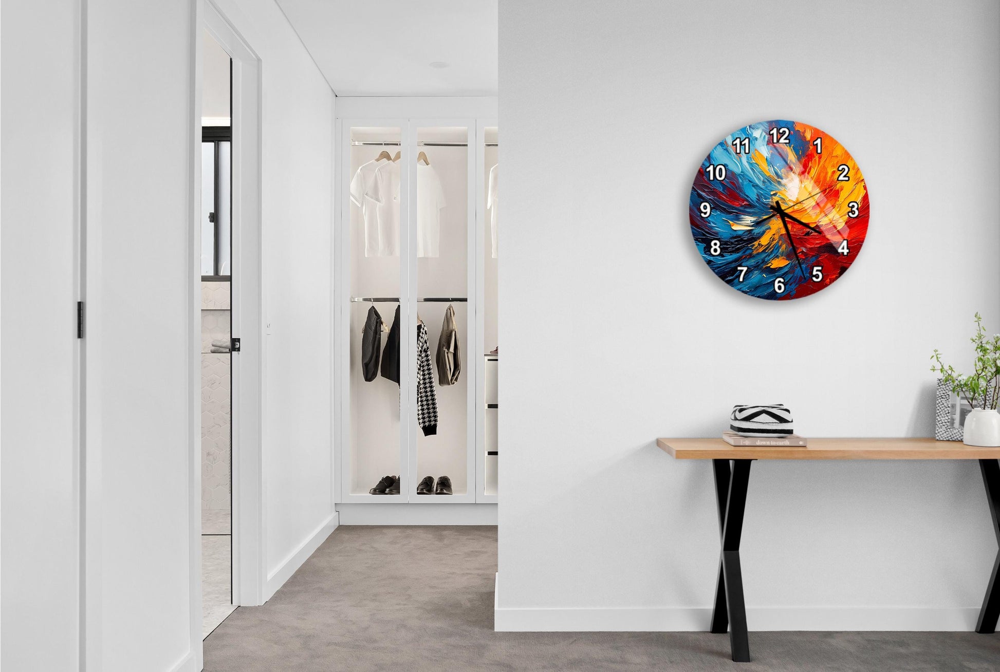 a modern hallway with a large, colorful clock on the wall. The hallway is clean and well-lit, with a wooden console table and a plant adding a touch of greenery to the space.