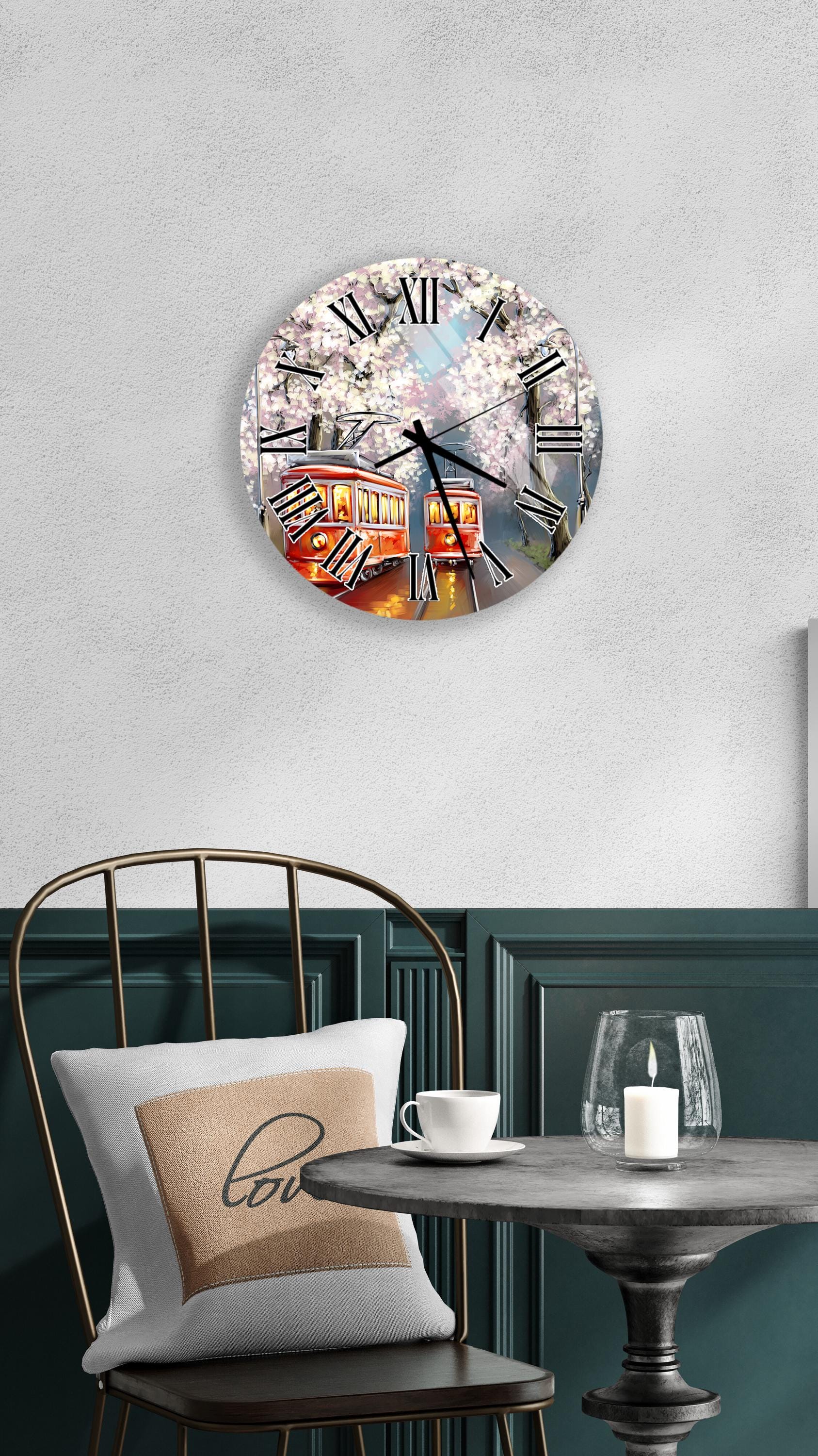 a wall clock with a floral design, a round table with a white candle, and a chair with a pillow.
