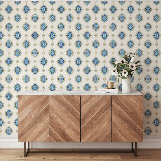 a wooden cabinet with a white marble top, set against a wall with a repeating pattern of blue and gold floral designs. The cabinet has a vase of flowers on top, and there is a book titled "Design" on the cabinet.
