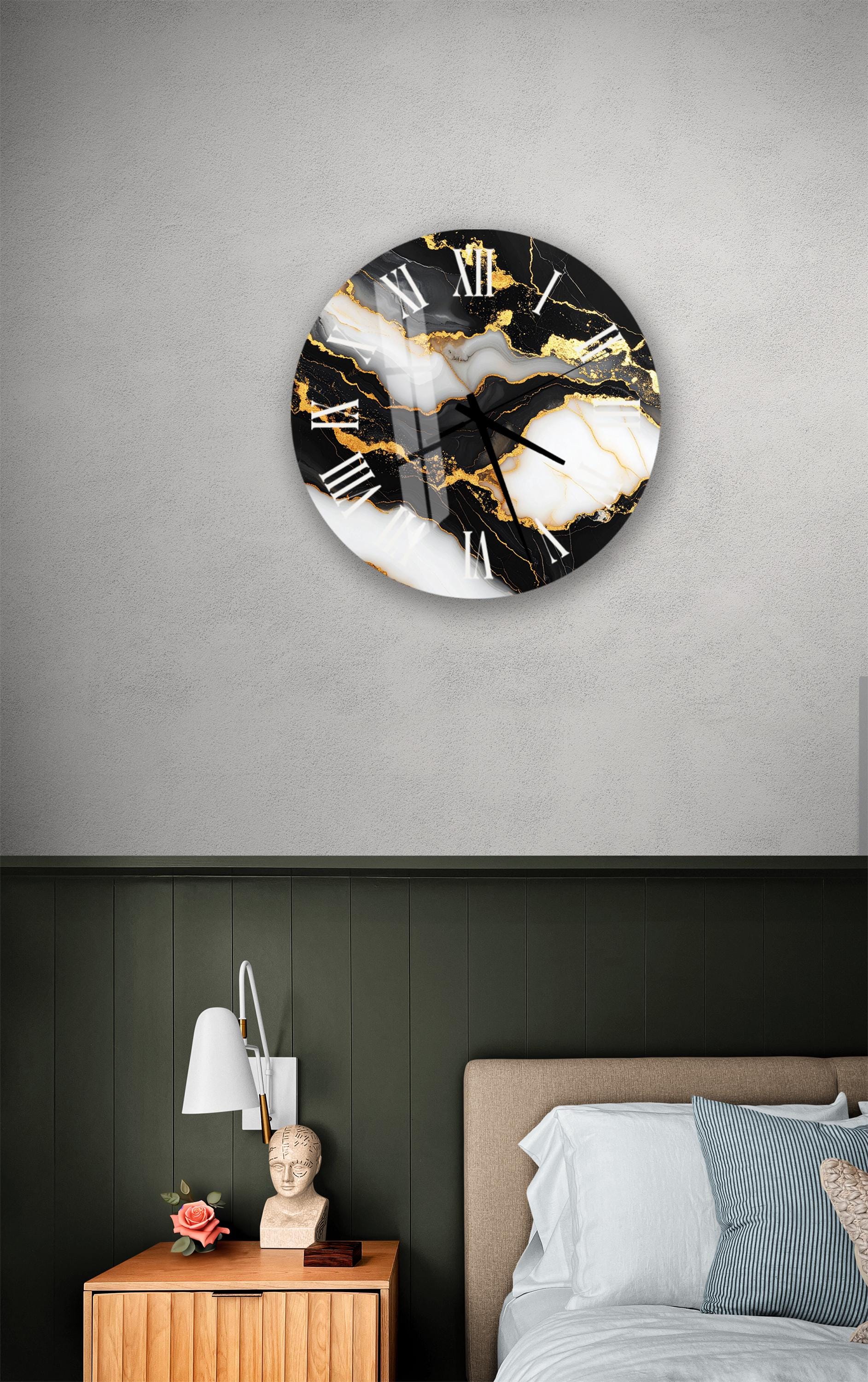a bedroom setting with a large black and white marble clock hanging on the wall above a bed. The clock has a striking black and white design with gold accents. The room also includes a nightstand with a lamp and a small statue, as well as a bed with white bedding and a striped pillow.