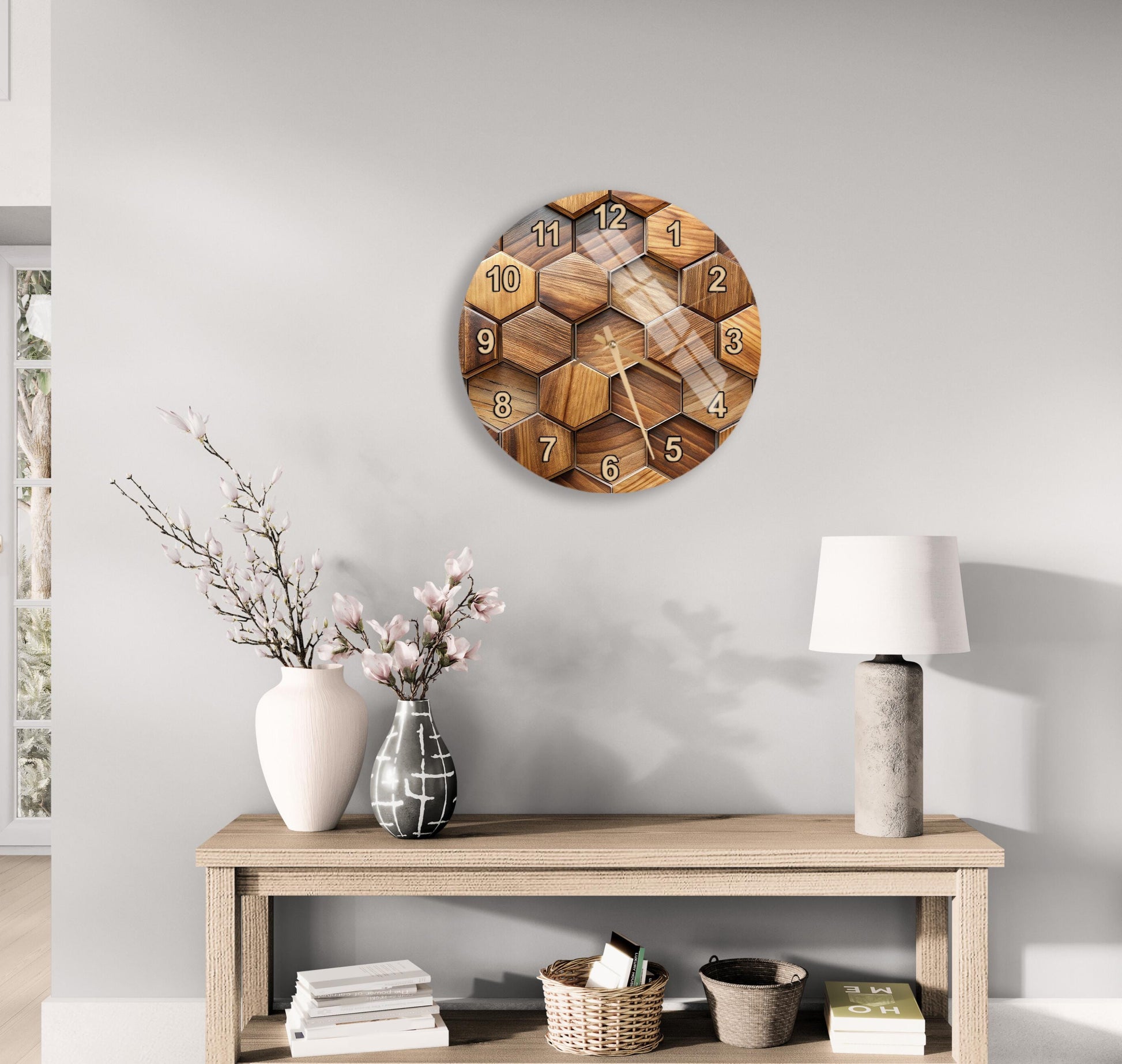 a wooden clock with a hexagonal design, mounted on a wall above a wooden table with various decorative items, including a vase with flowers, a lamp, and a stack of books.