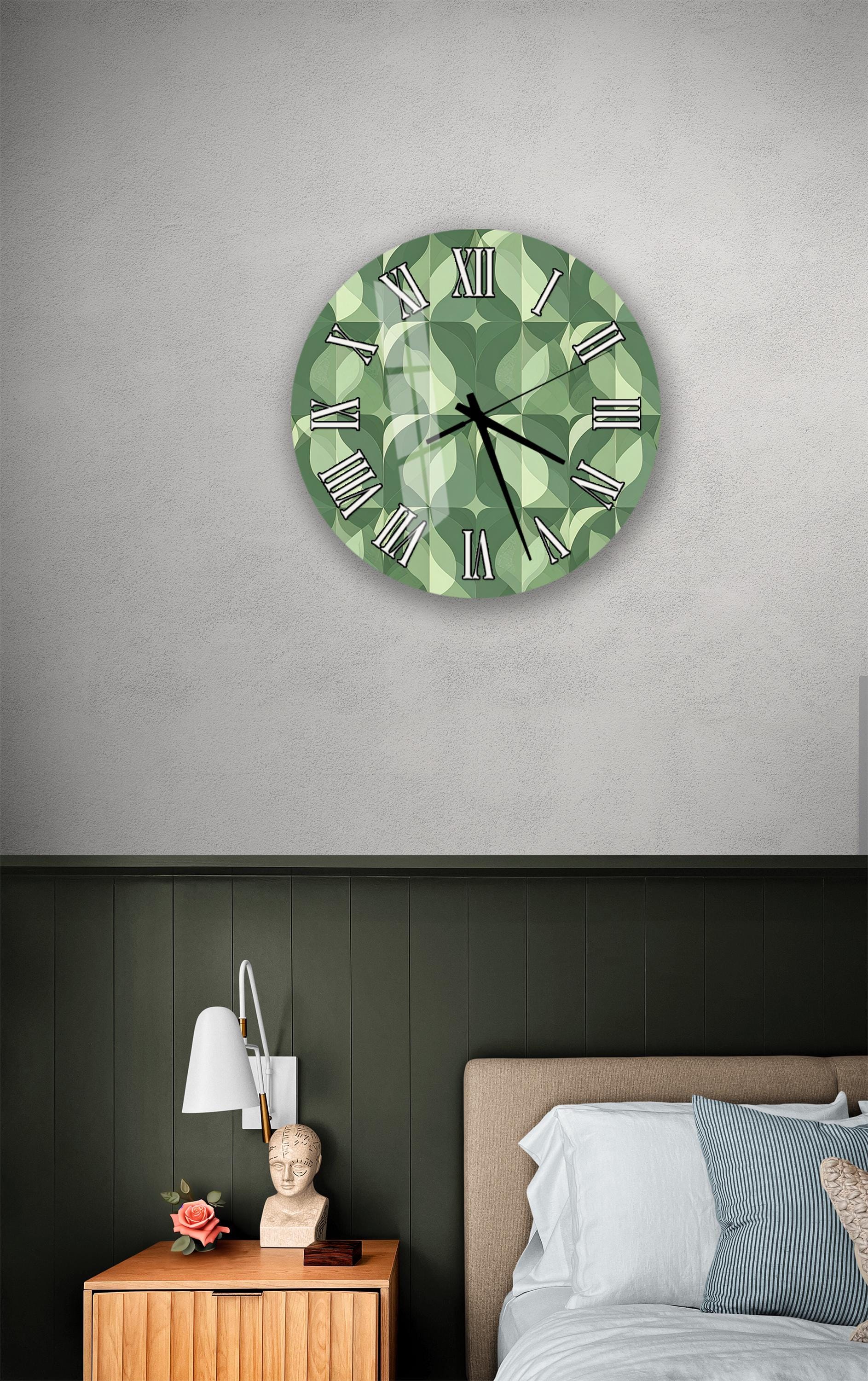 a bedroom setting with a large green wall clock hanging above a bed. The clock has a unique geometric pattern and is positioned at eye level. The bed is covered with white sheets and has a wooden headboard. There is also a nightstand with a lamp and a small statue on top.