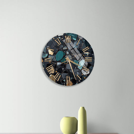 a modern clock with a black and gold design, mounted on a wall above a wooden dresser. The dresser has three drawers and contains a yellow vase and a small green sculpture.