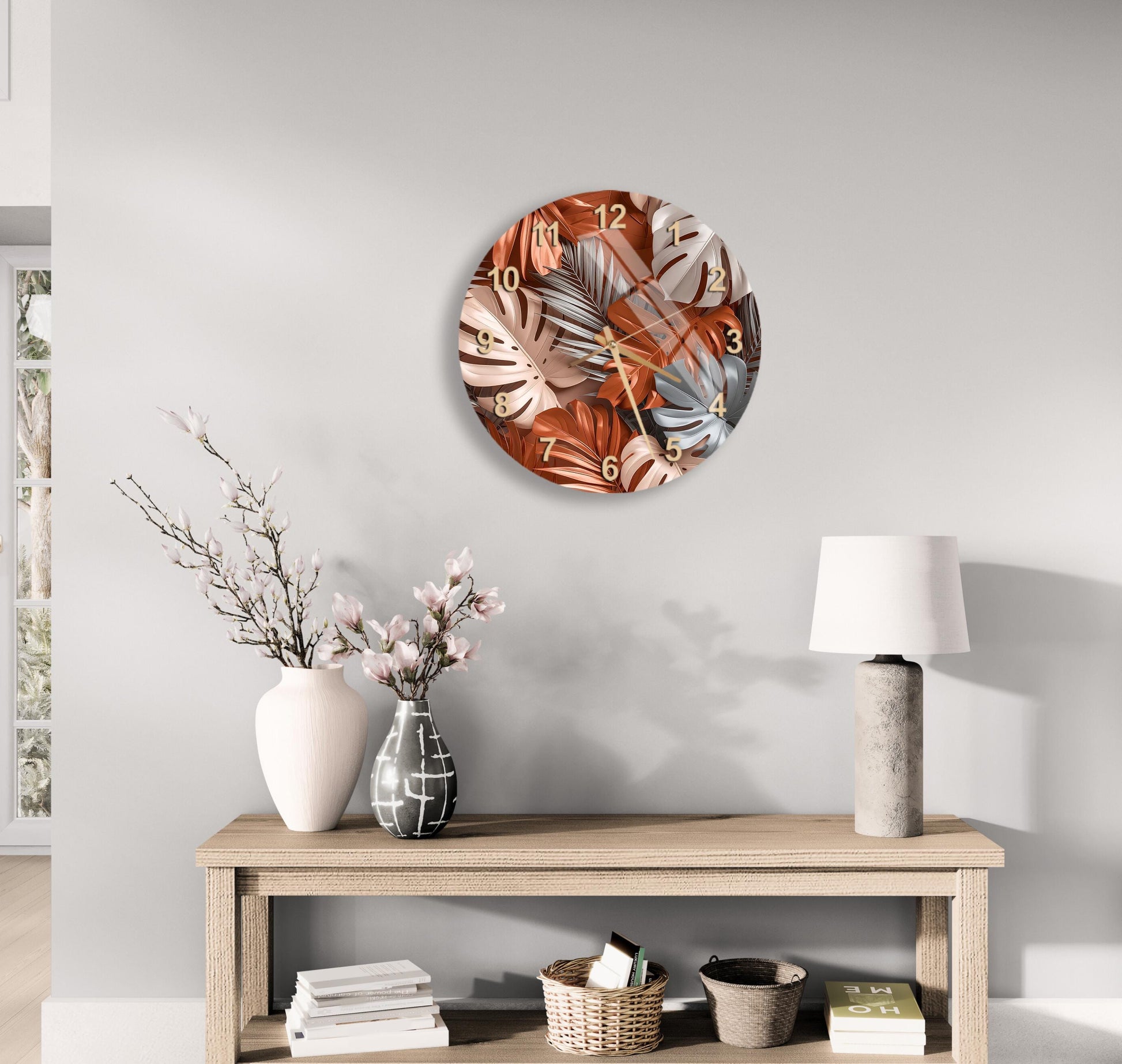 a modern living room with a round wall clock displaying a tropical leaf pattern, a wooden table with a lamp, a vase with flowers, and a stack of books.
