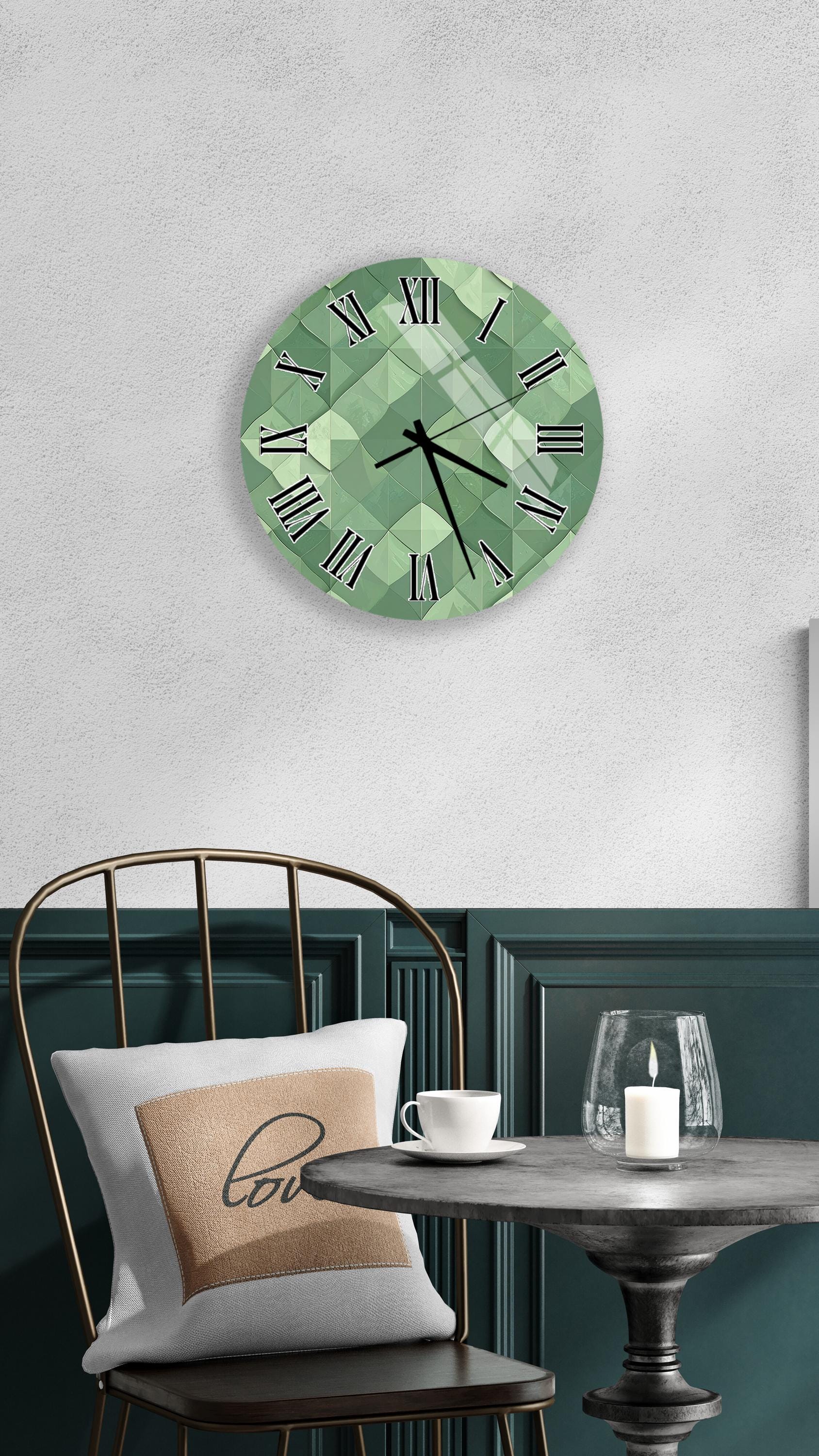 a modern green wall clock with a geometric design, mounted on a white wall above a black metal chair. The chair is positioned in front of a small round table with a white tablecloth, and a candle is lit on the table.