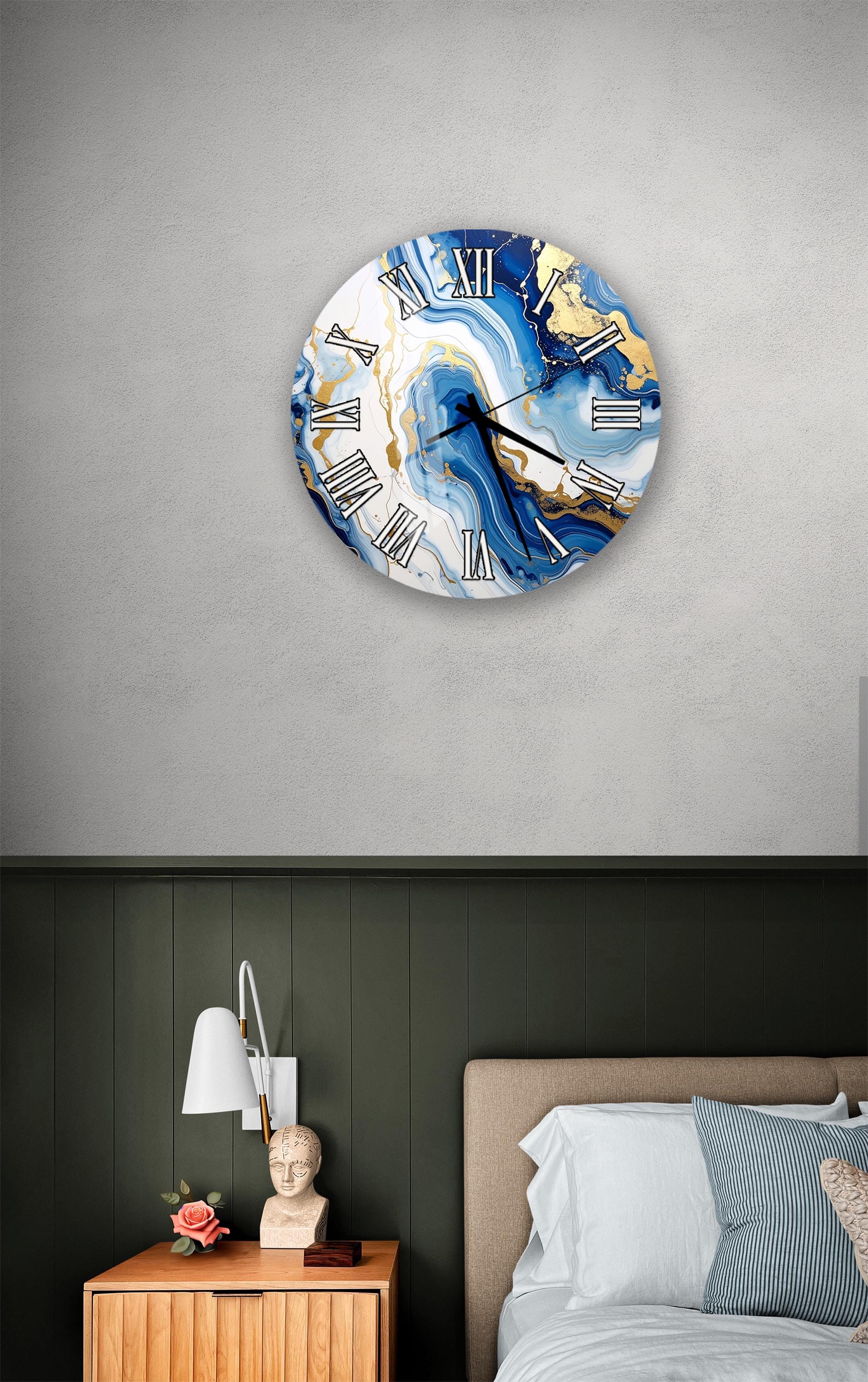 a bedroom setting with a large, round wall clock with a marble-like design in blue and gold colors. The clock is mounted on a wall above a bed with a wooden headboard. The room also includes a nightstand with a lamp and a small statue or bust.