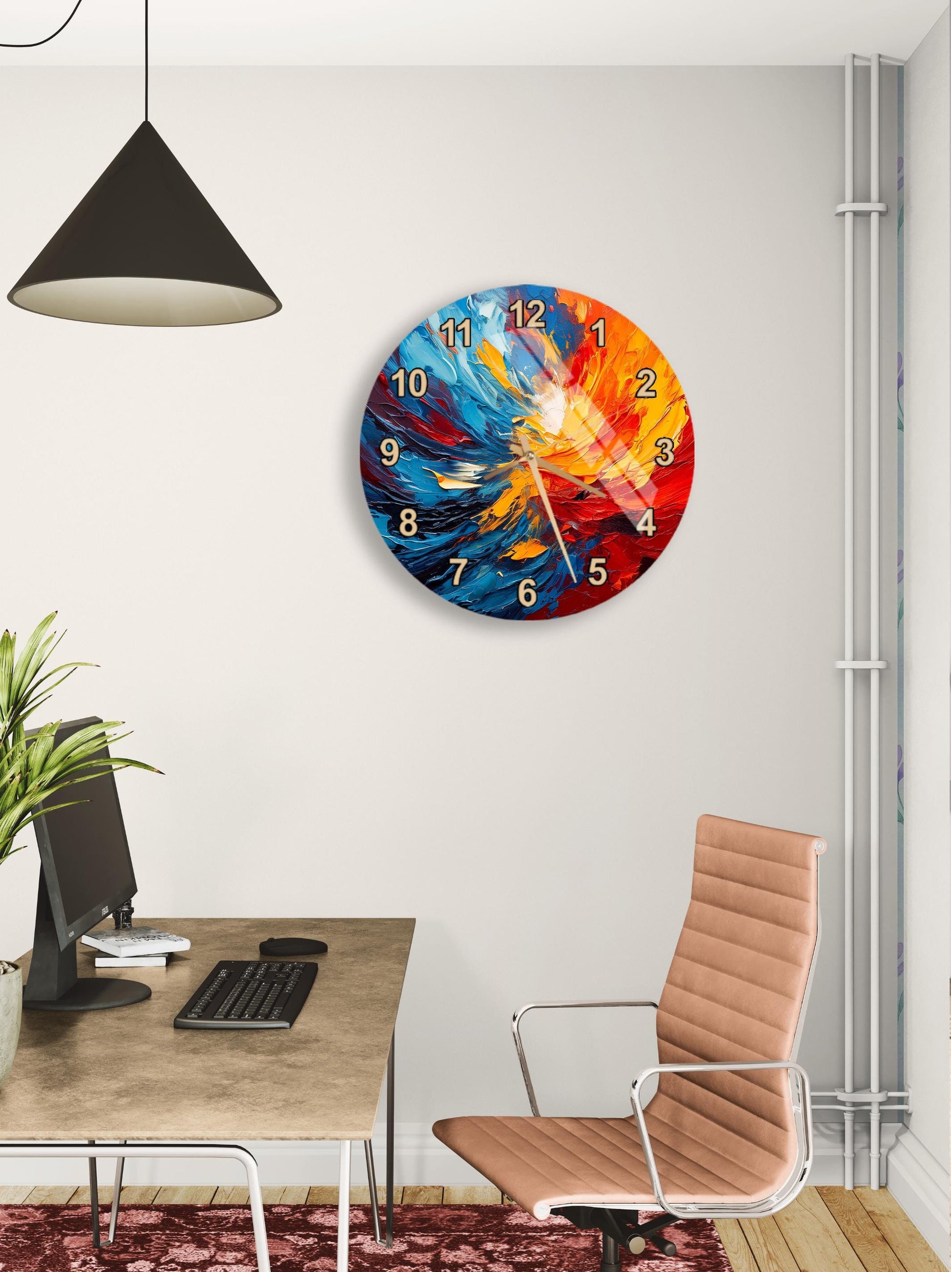 a modern office space with a large, colorful wall clock hanging on the wall. The clock has a vibrant design with swirling patterns in shades of blue, orange, and red. The office space includes a desk with a computer monitor, keyboard, and mouse, as well as a comfortable office chair. A potted plant is also present in the room, adding a touch of greenery to the space.