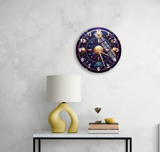 May include: A celestial-themed wall clock with gold and purple accents. The clock face features planets, stars, and celestial symbols. The numbers are clearly visible, and the clock hands are elegantly designed. The clock has a diameter of approximately 12 inches. The clock is displayed on a wall, above a table with a lamp and other decorative items. The overall style is modern and sophisticated, suitable for a home or office setting.