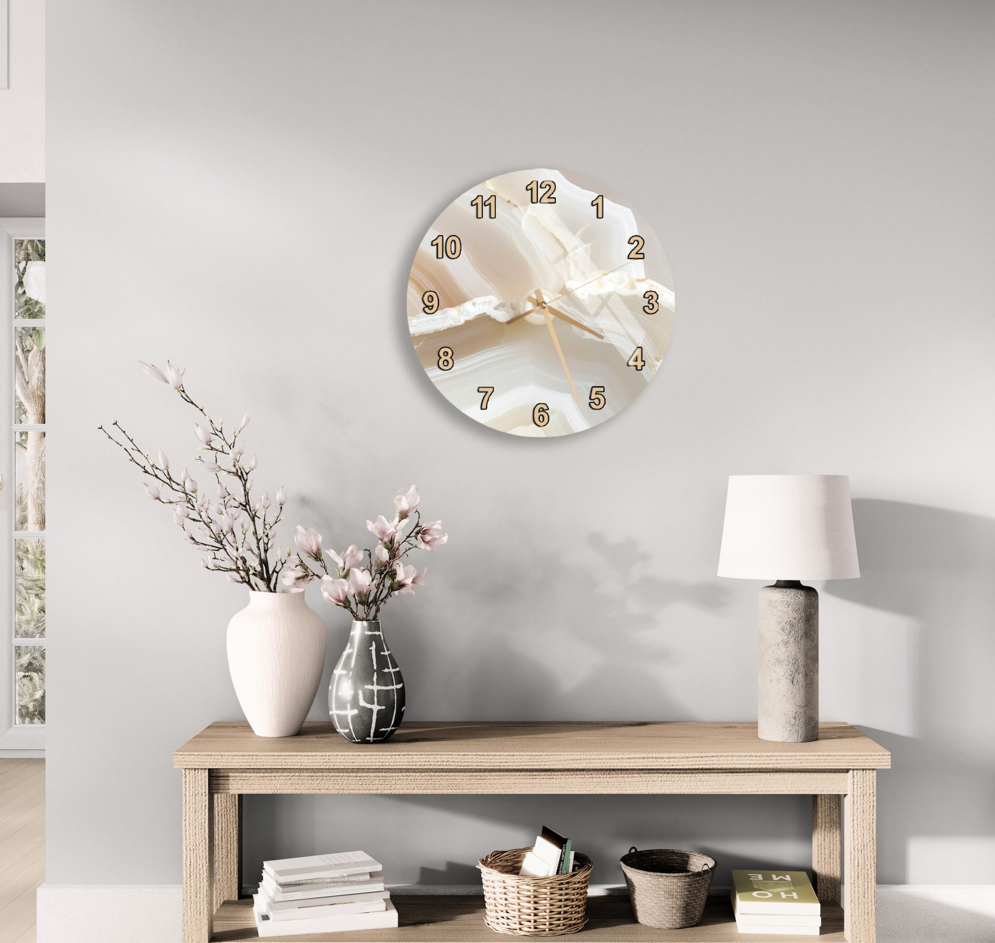 a modern and minimalist living room with a round wall clock, a wooden table with a lamp, a vase with flowers, and a stack of books.