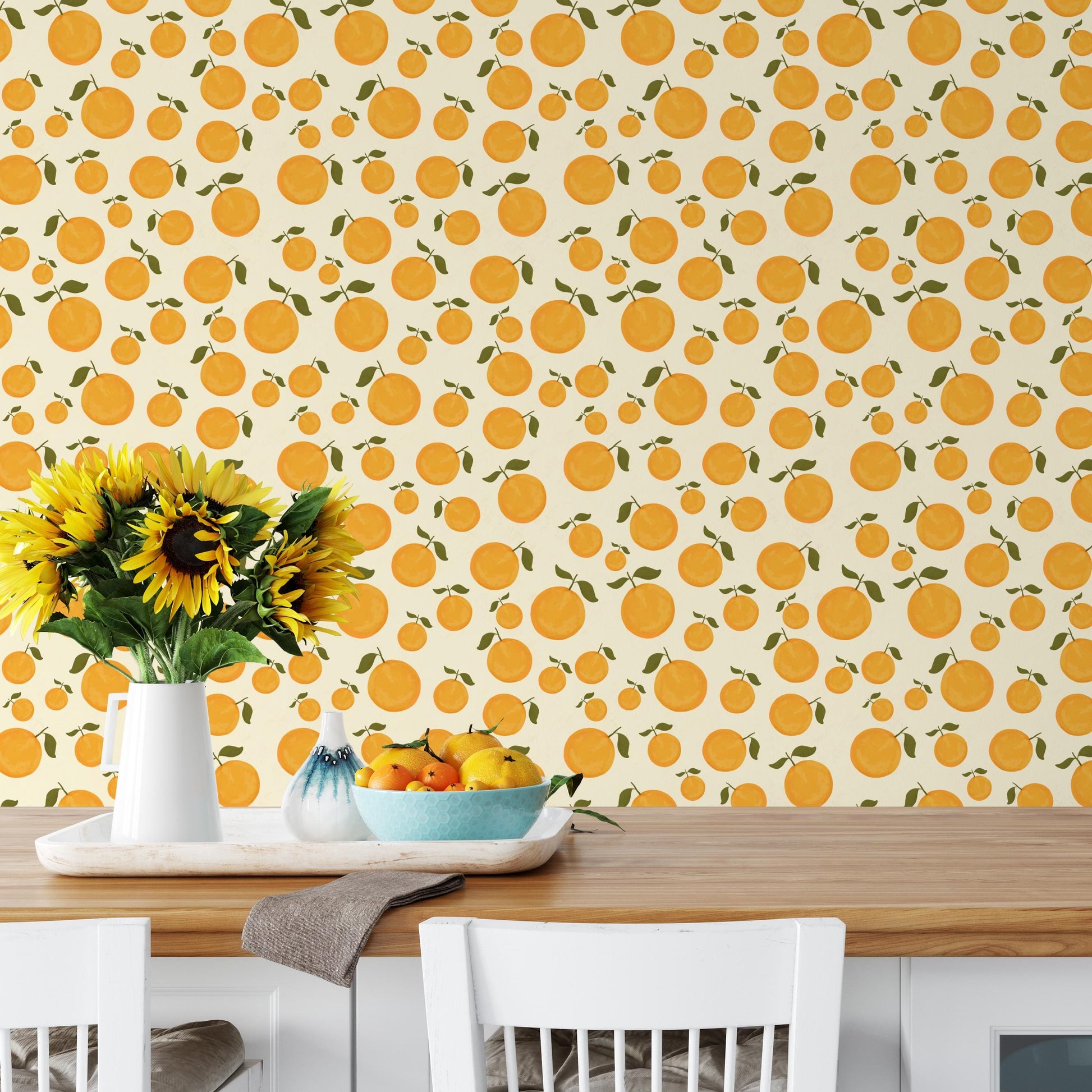 a kitchen scene with a wooden table, a white vase with sunflowers, a bowl of fruit, and a wall with a repeating pattern of orange and green circles.