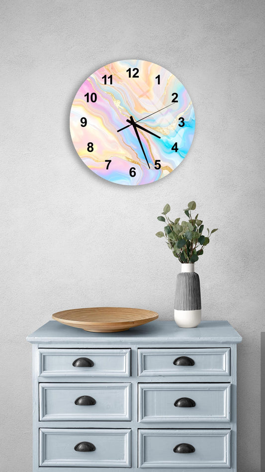 a wall clock with a colorful, abstract design, mounted on a wall above a light blue dresser with six drawers. The dresser also has a vase with greenery on it, and there is a wooden plate on top of the dresser.